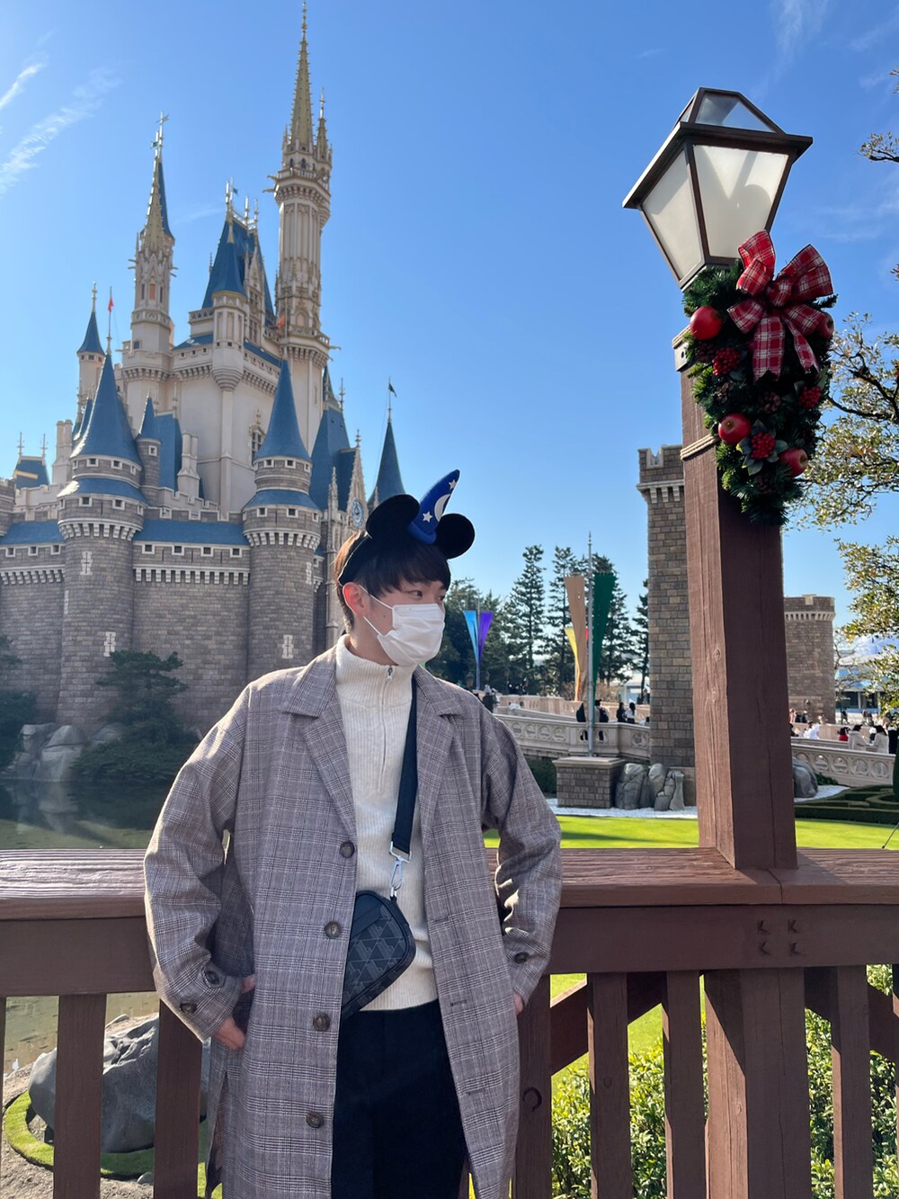 ベージュ系のトレンチコート、ホワイト系のニット/セーター、ブラック系のショルダーバッグを着用したメンズの冬コーディネートの2枚目の写真