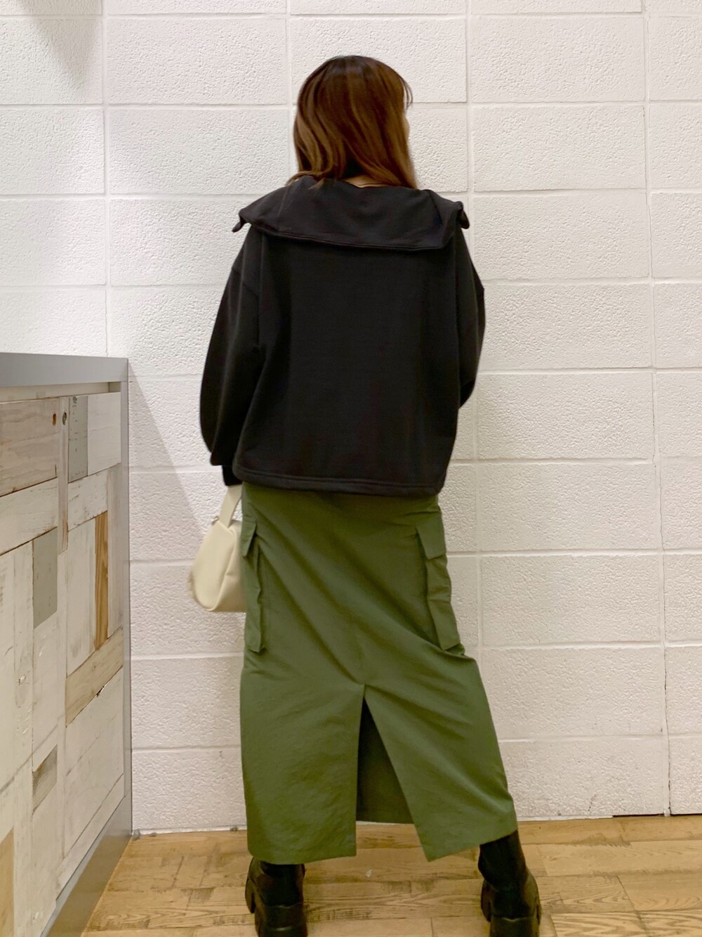 グレー系のトップス、グリーン系のスカート、ホワイト系のバッグを着用したレディースの秋コーディネートの4枚目の写真