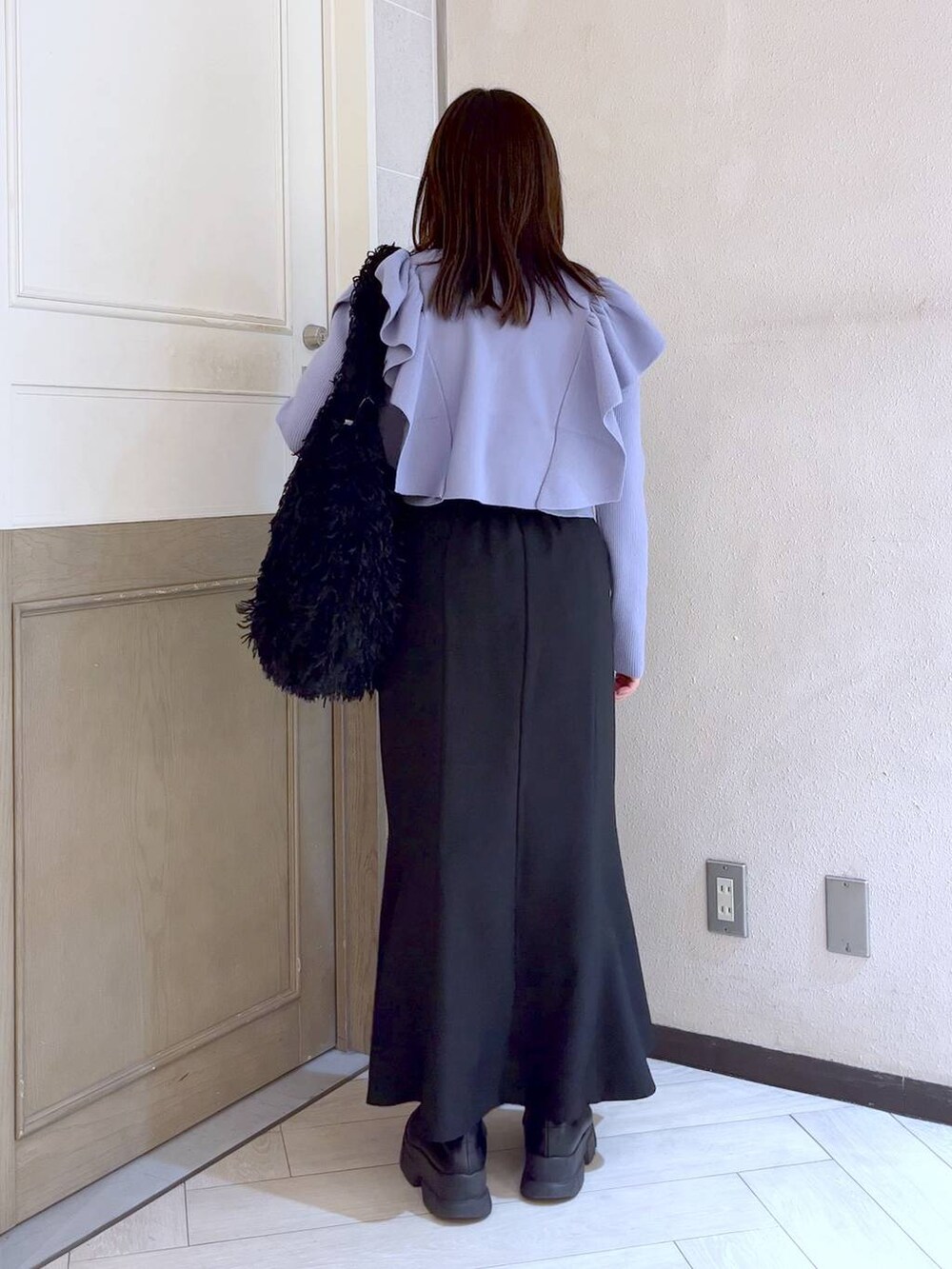 ブラック系のスカート、ブラック系のブーツ、パープル系のニット/セーターを着用したレディースの冬コーディネートの4枚目の写真