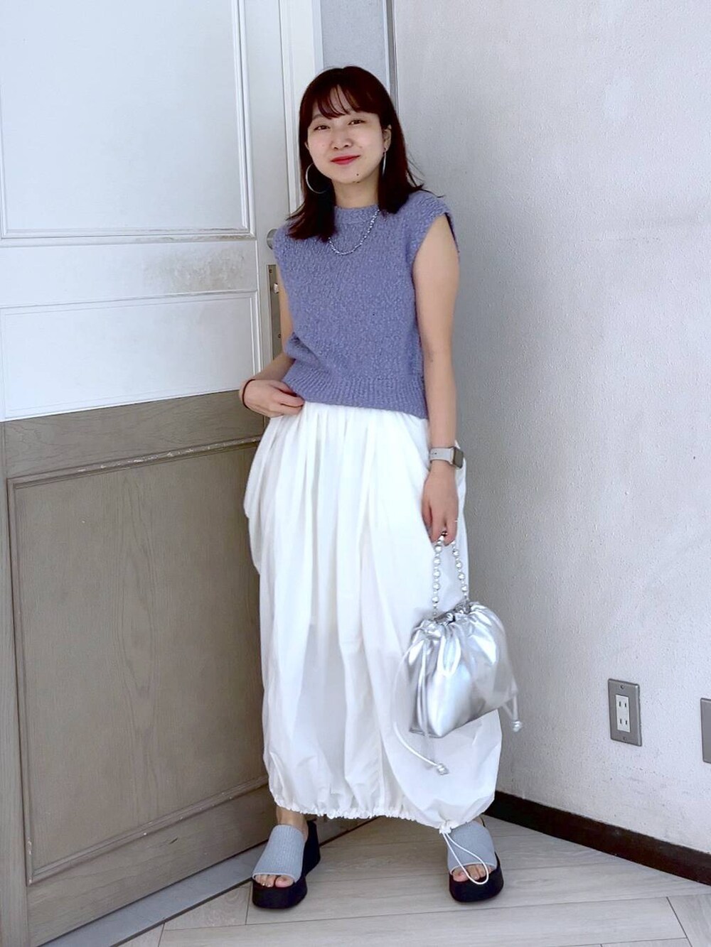 シルバー系のサンダル、ホワイト系のスカート、シルバー系のショルダーバッグを着用したレディースの夏コーディネートの2枚目の写真