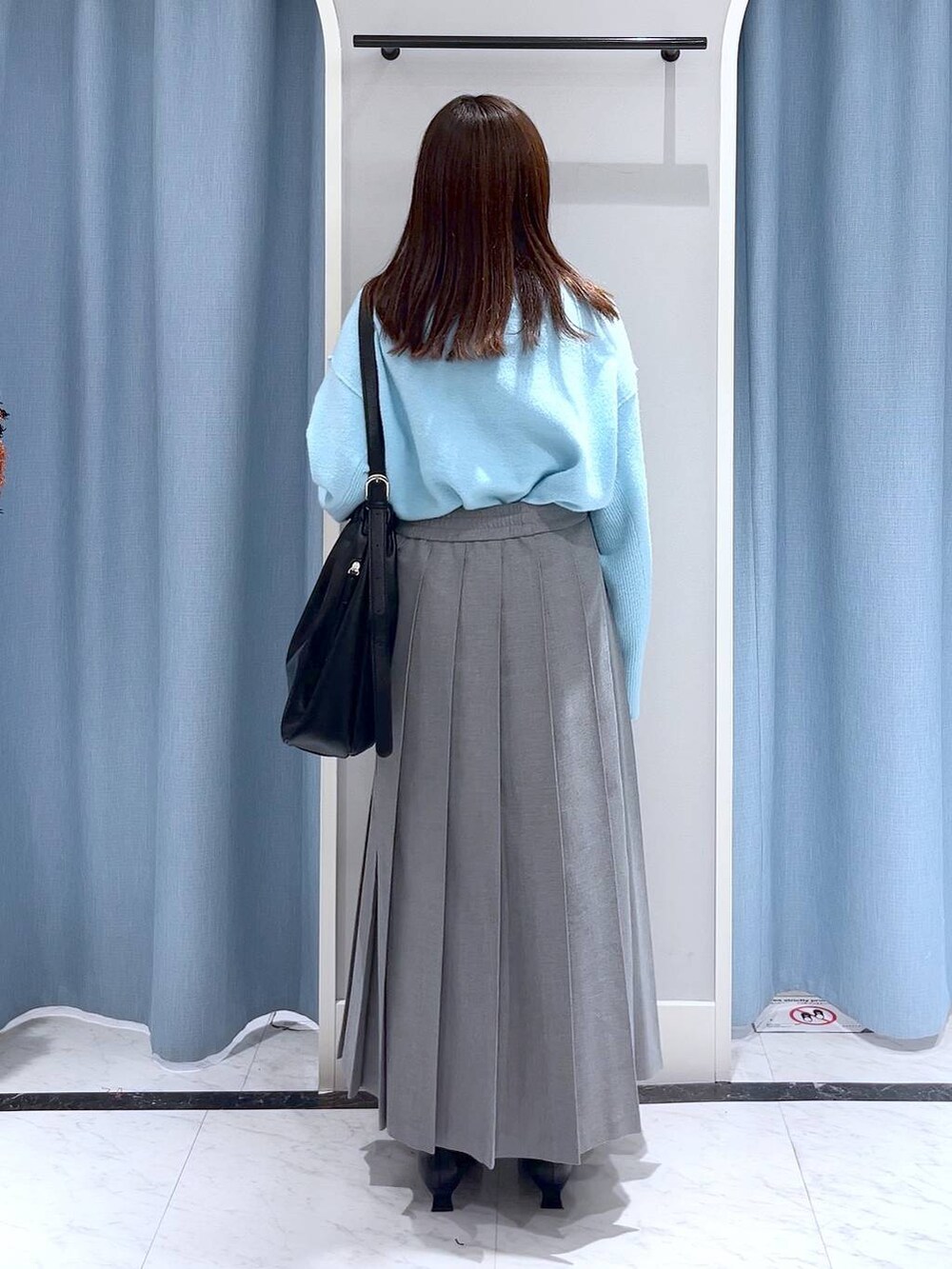 ブルー系のニット/セーター、ブラック系のブーツ、ブラック系のショルダーバッグを着用したレディースの冬コーディネートの3枚目の写真