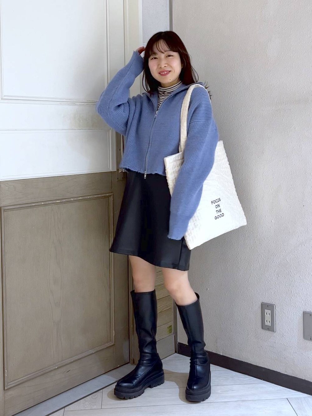 ホワイト系のTシャツ/カットソー、ホワイト系のトートバッグ、ブラック系のブーツを着用したレディースの冬コーディネートの2枚目の写真