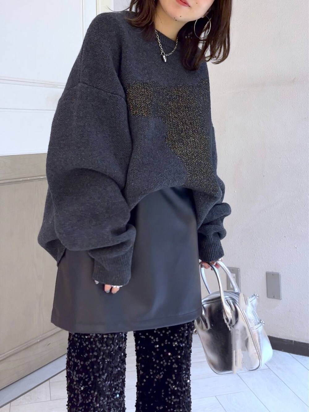 ブラック系のブーツ、シルバー系のボストンバッグ、ブラック系のスカートを着用したレディースの冬コーディネートの5枚目の写真