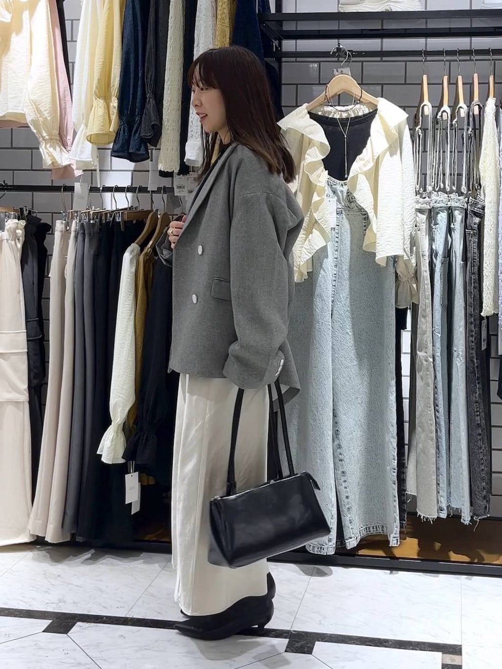 ホワイト系のスカート、ブラック系のショルダーバッグ、ブラック系のブーツを着用したレディースの冬コーディネートの2枚目の写真