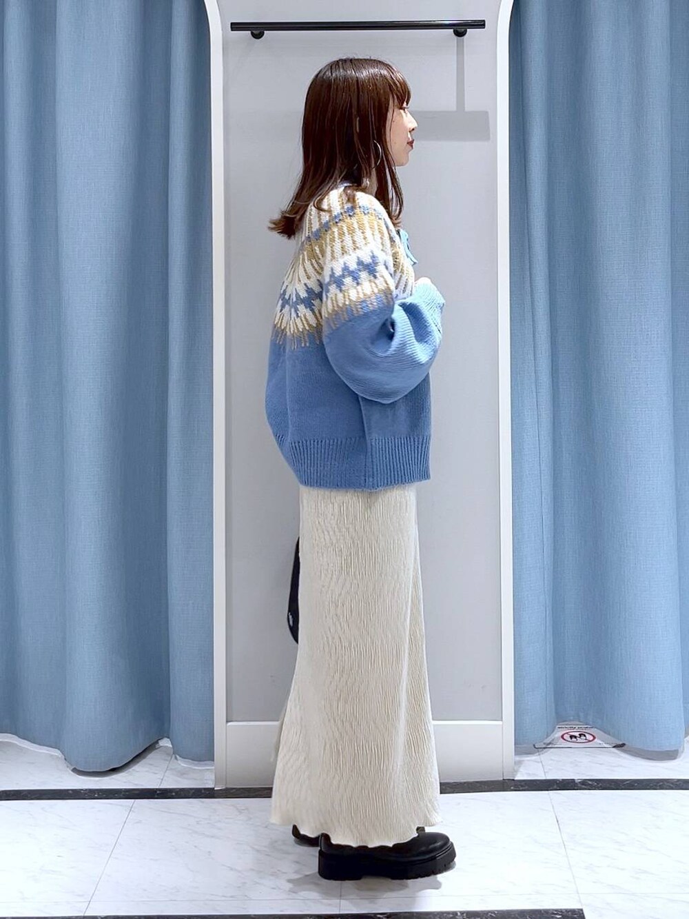 ブラック系のブーツ、ホワイト系のスカート、ブラック系のハンドバッグを着用したレディースの冬コーディネートの5枚目の写真