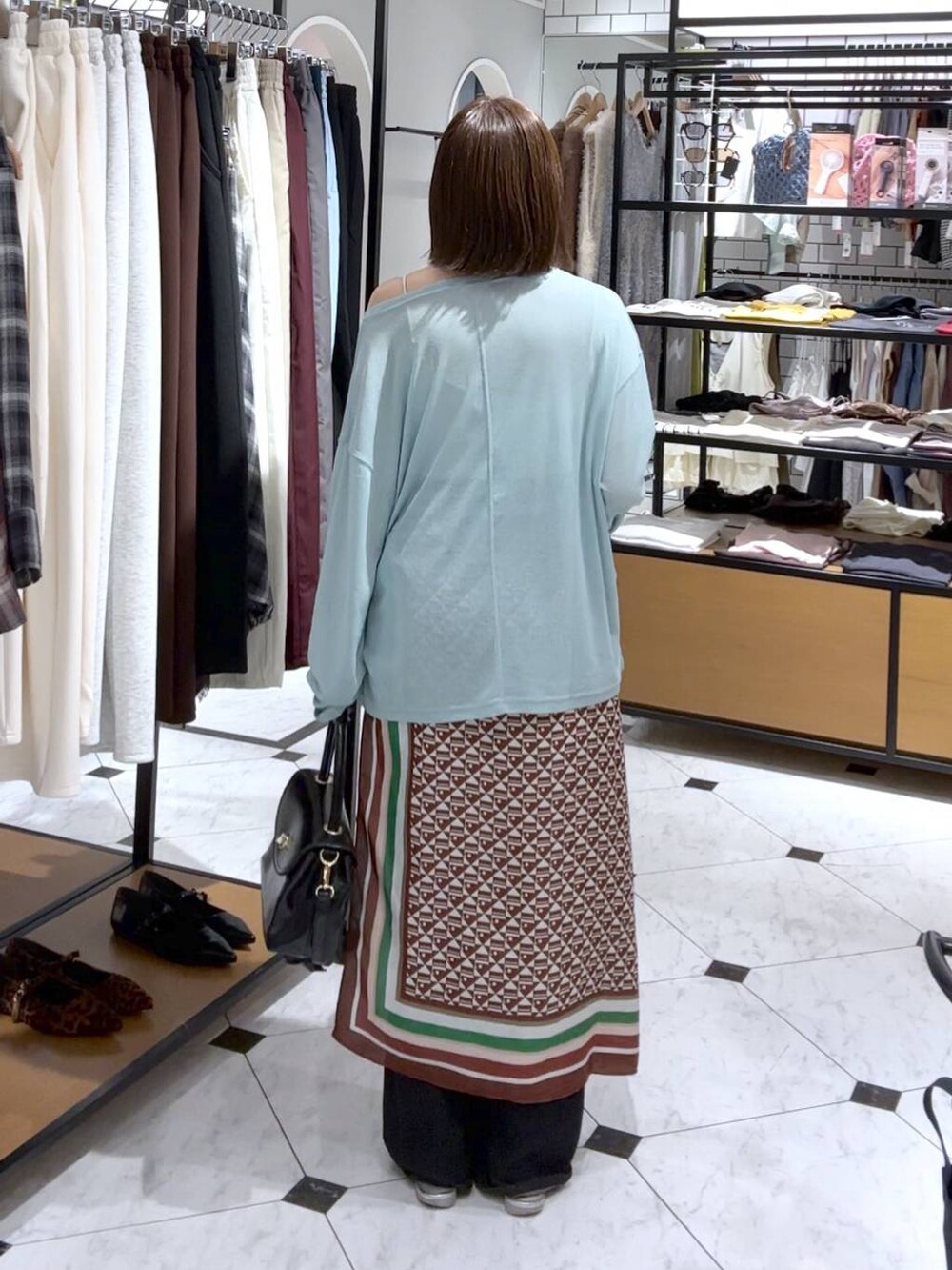 シルバー系のサンダル、ブラック系のデニムパンツ、ブラック系のボストンバッグを着用したレディースの夏コーディネートの3枚目の写真