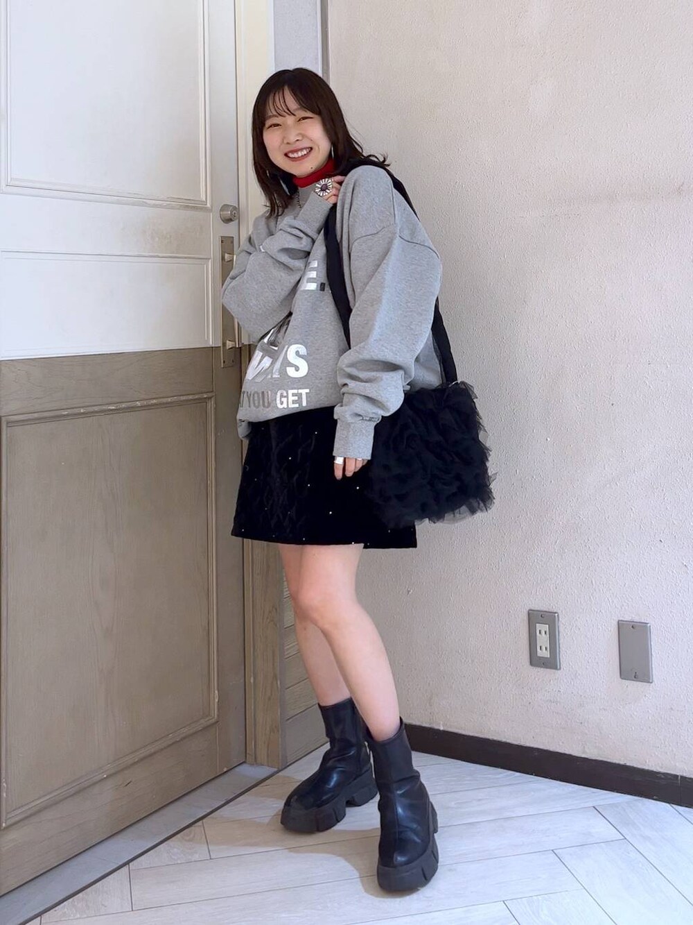 ブラック系のブーツ、レッド系のニット/セーター、ブラック系のショルダーバッグを着用したレディースの冬コーディネートの4枚目の写真