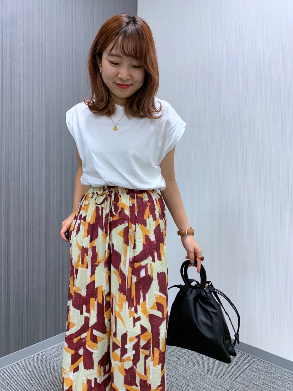 ホワイト系のTシャツ/カットソー、レッド系のパンツ、ブラック系のショルダーバッグを着用したレディースの秋コーディネートの3枚目の写真