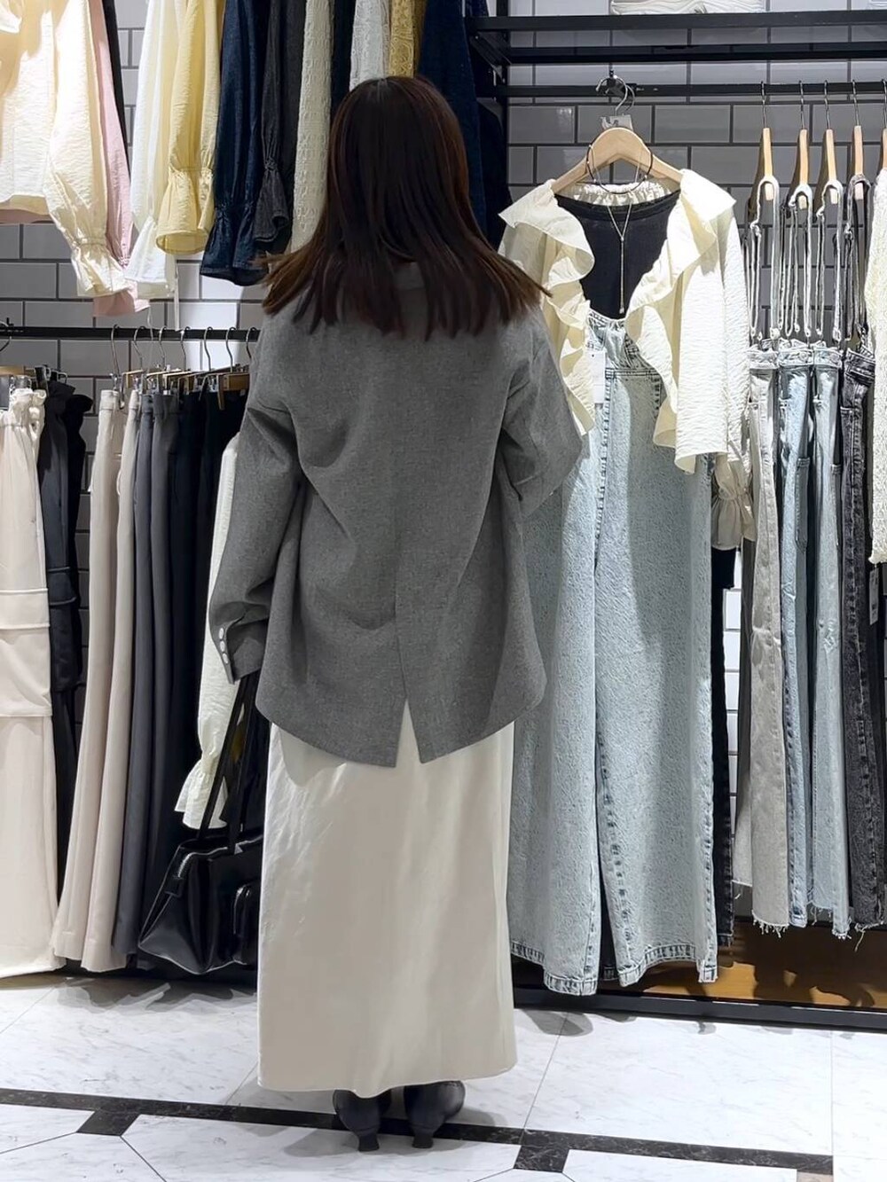 ホワイト系のスカート、ブラック系のショルダーバッグ、ブラック系のブーツを着用したレディースの冬コーディネートの3枚目の写真