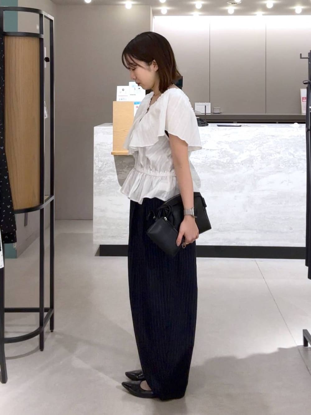 ブルー系のその他パンツ、ブラック系のパンプス、ブラック系のトートバッグを着用したレディースの春コーディネートの2枚目の写真