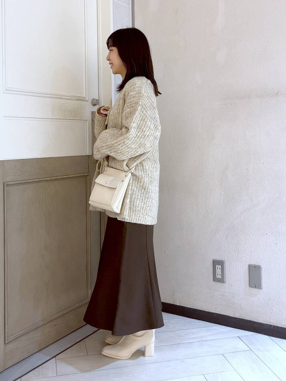 ホワイト系のショルダーバッグ、ブラウン系のスカート、ホワイト系のパンプスを着用したレディースの冬コーディネートの3枚目の写真