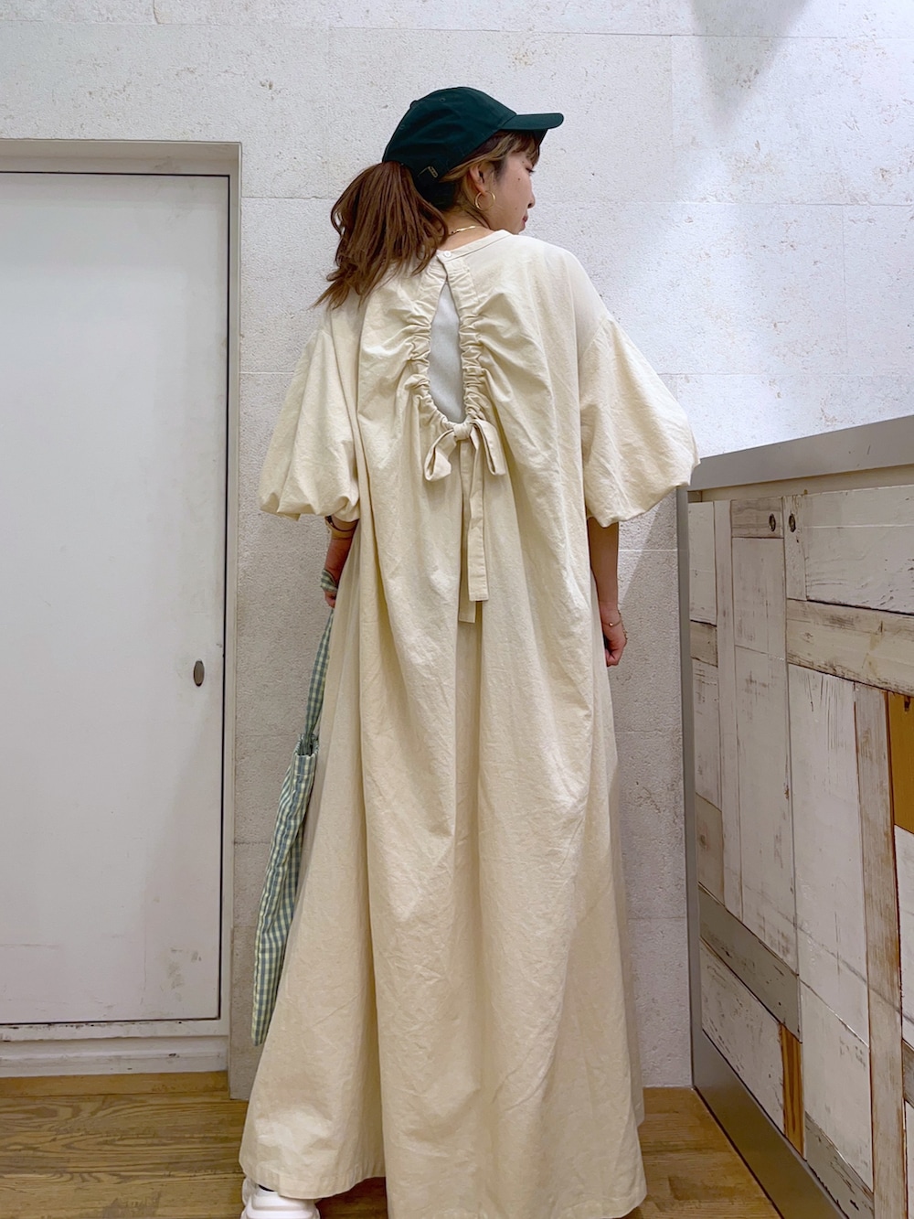 ホワイト系のワンピース、ホワイト系のシューズ、グリーン系のキャップを着用したレディースの春コーディネートの3枚目の写真