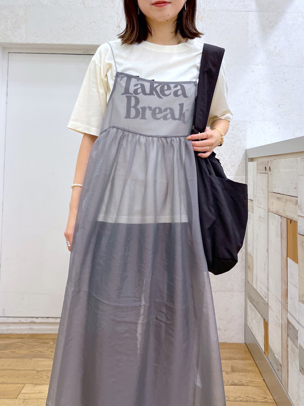 グレー系のワンピース、ホワイト系のシューズ、ブラック系のバッグを着用したレディースの夏コーディネートの5枚目の写真