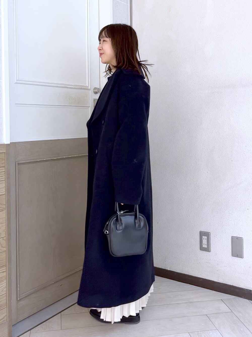 ブルー系のステンカラーコート、ブラック系のニット/セーター、ブラック系のブーツを着用したレディースの冬コーディネートの3枚目の写真