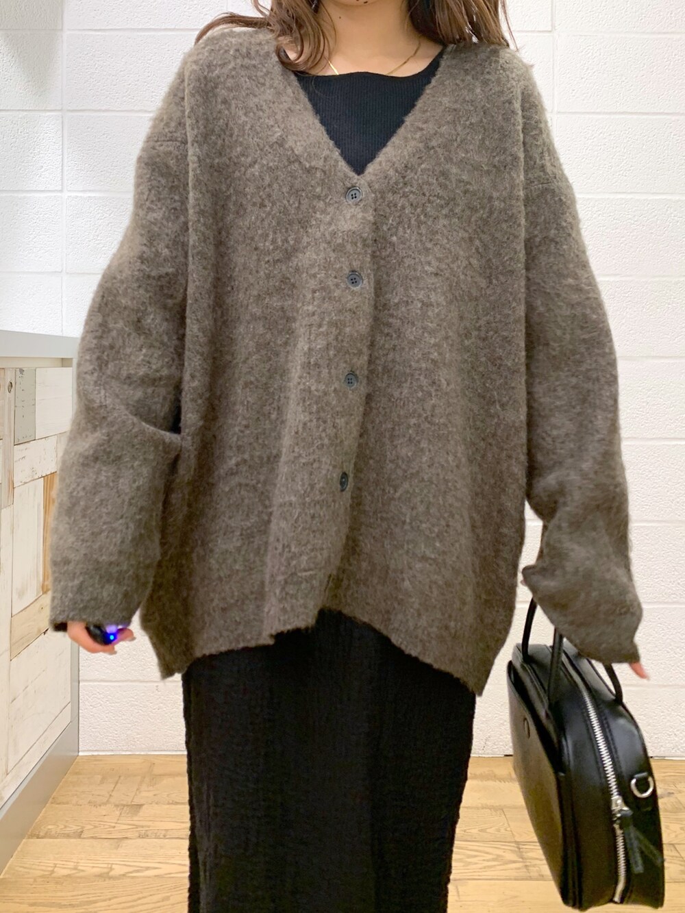 ブラウン系のカーディガン/ボレロ、ブラック系のスカート、ブラック系のバッグを着用したレディースの秋コーディネートの5枚目の写真