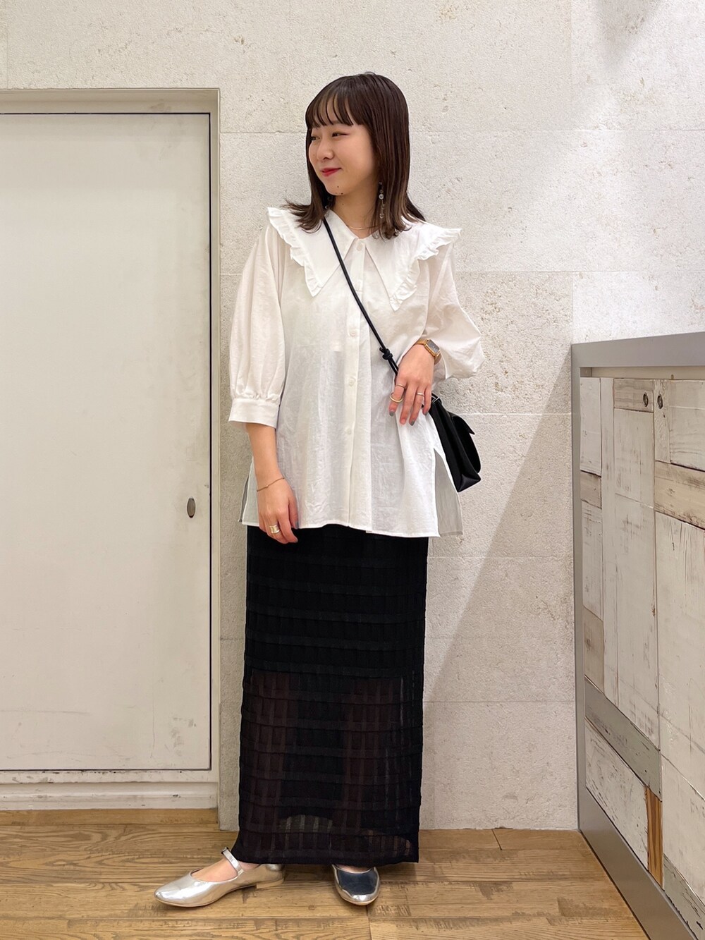 ホワイト系のトップス、ブラック系のスカート、ブラック系のバッグを着用したレディースの春コーディネートの2枚目の写真