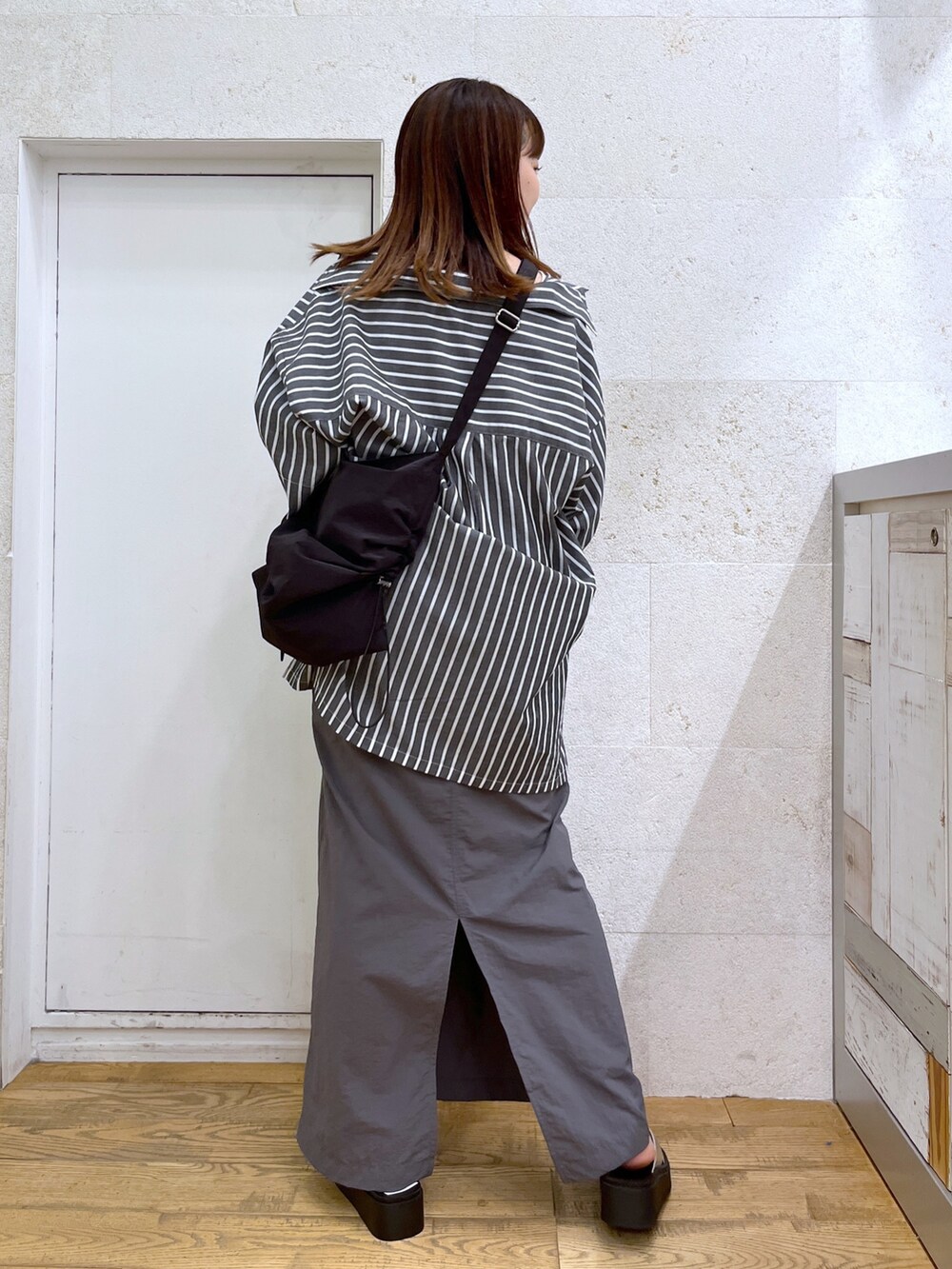 グレー系のワンピース、ブラック系のトップス、ブラック系のショルダーバッグを着用したレディースの夏コーディネートの5枚目の写真