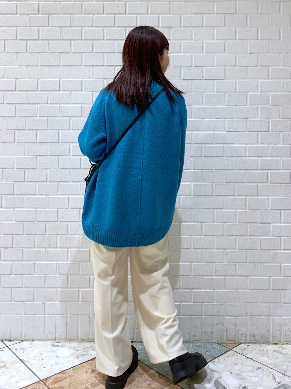 ブルー系のトップス、ブラック系のバッグ、ブラック系のブーツを着用したレディースの冬コーディネートの4枚目の写真