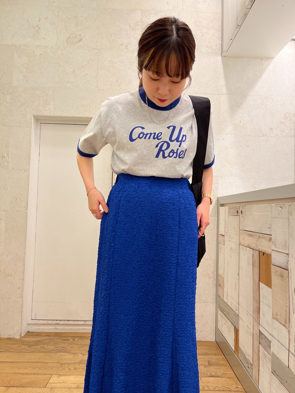 グレー系のTシャツ/カットソー、ブルー系のスカート、ブラック系のシューズを着用したレディースの春コーディネートの3枚目の写真
