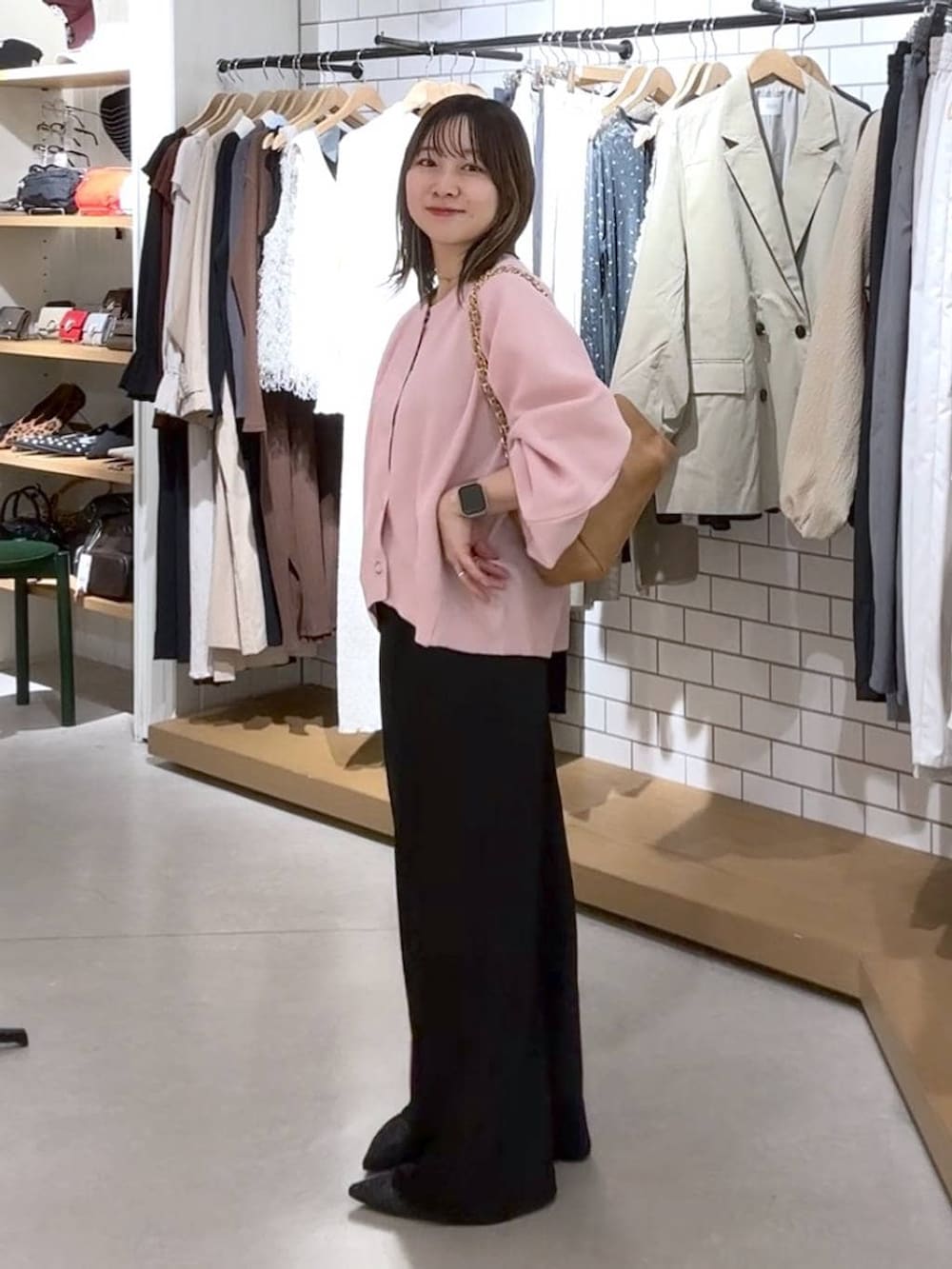 ブラック系のスカート、ベージュ系のショルダーバッグ、ブラック系のパンプスを着用したレディースの春コーディネートの2枚目の写真