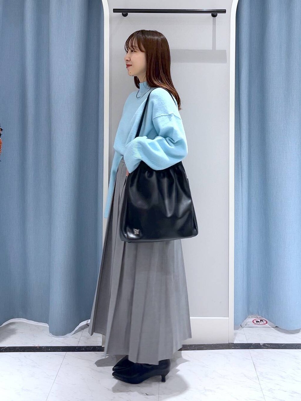 ブルー系のニット/セーター、ブラック系のブーツ、ブラック系のショルダーバッグを着用したレディースの冬コーディネートの2枚目の写真