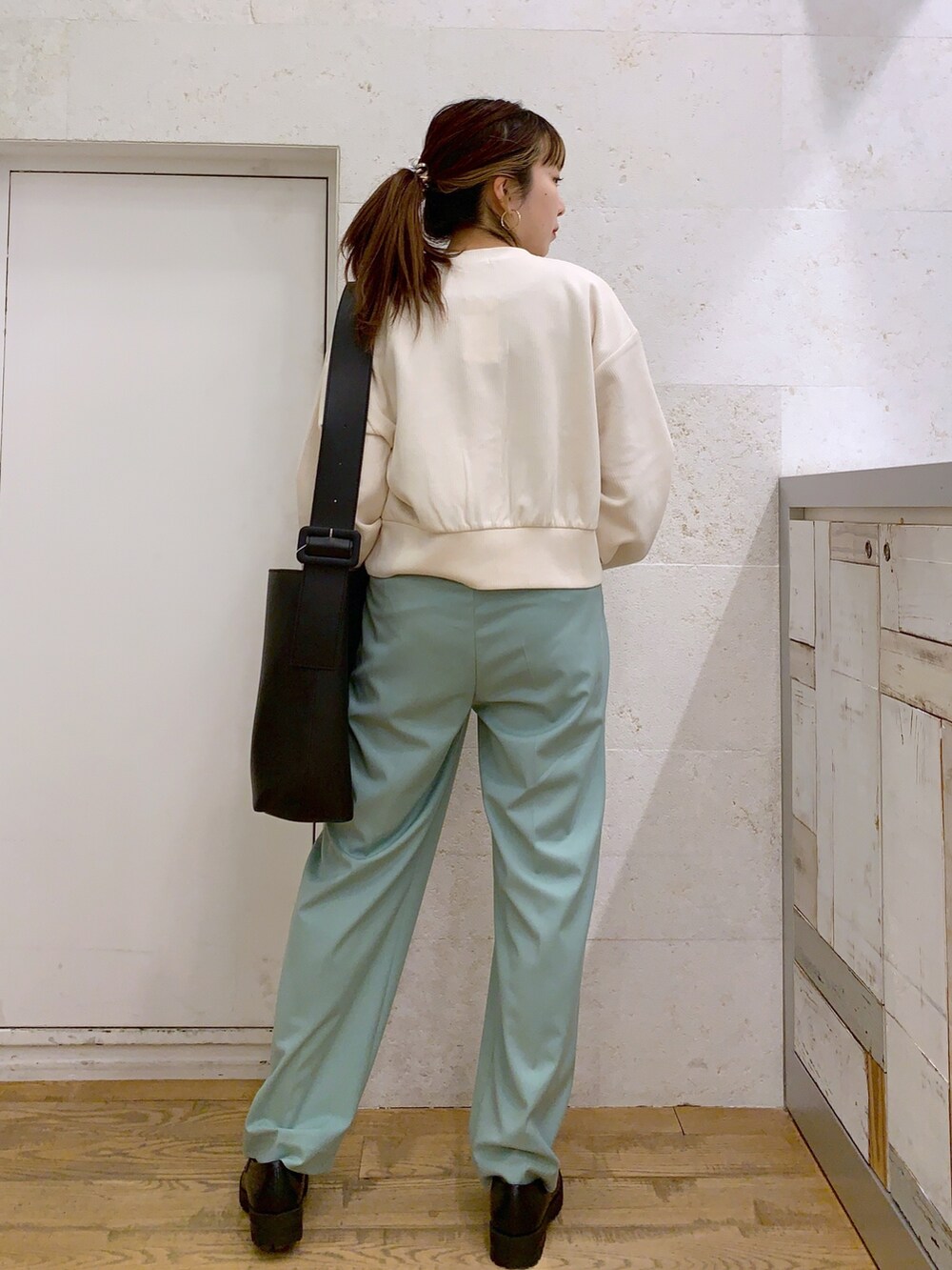 ホワイト系のトップス、グリーン系のパンツ、ブラック系のバッグを着用したレディースの春コーディネートの3枚目の写真
