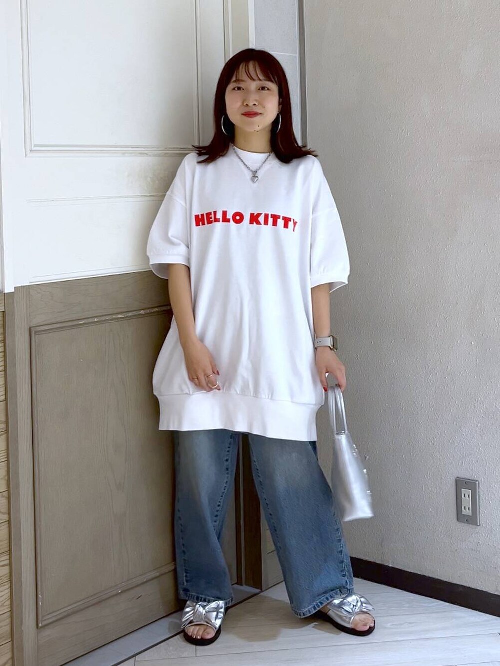 シルバー系のショルダーバッグ、ブルー系のデニムパンツ、シルバー系のサンダルを着用したレディースの夏コーディネートの2枚目の写真