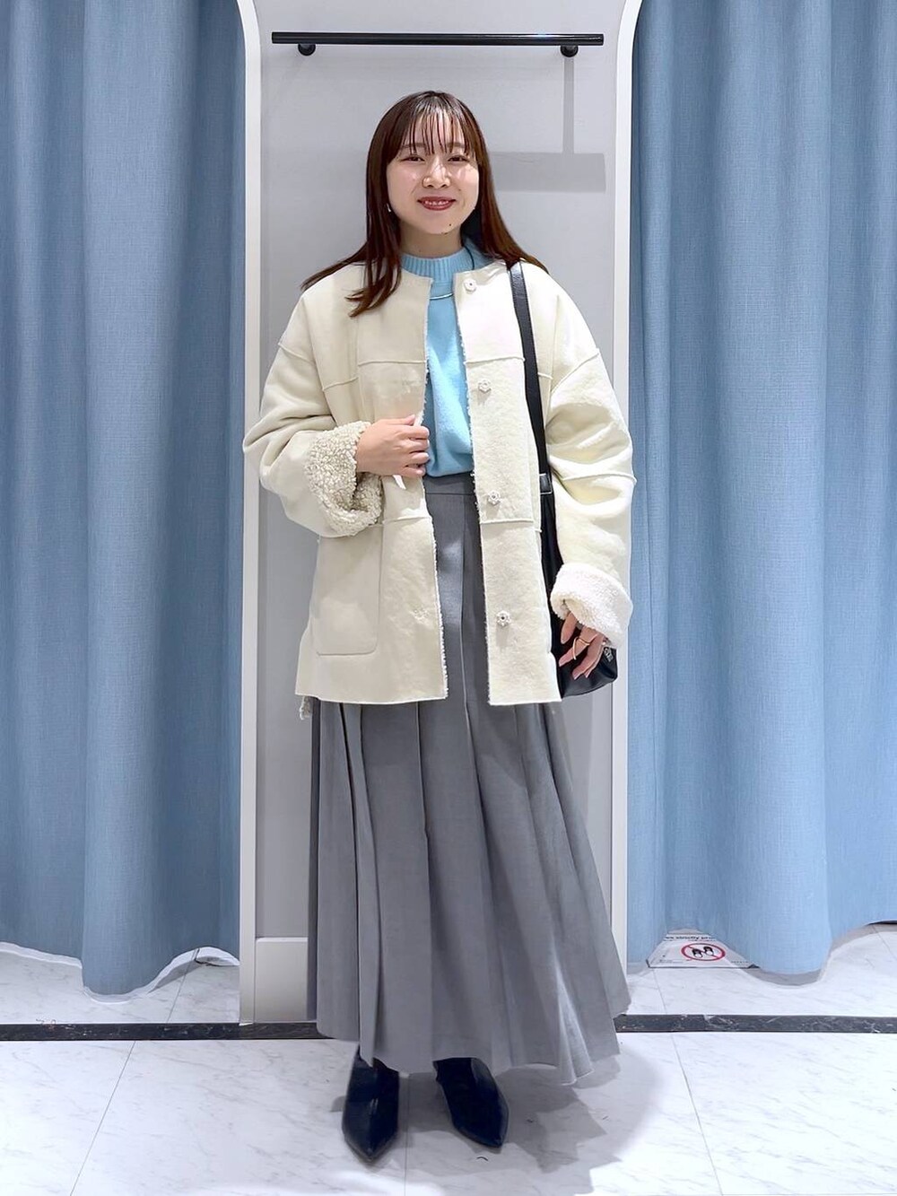 ブルー系のニット/セーター、ブラック系のブーツ、ブラック系のショルダーバッグを着用したレディースの冬コーディネートの3枚目の写真