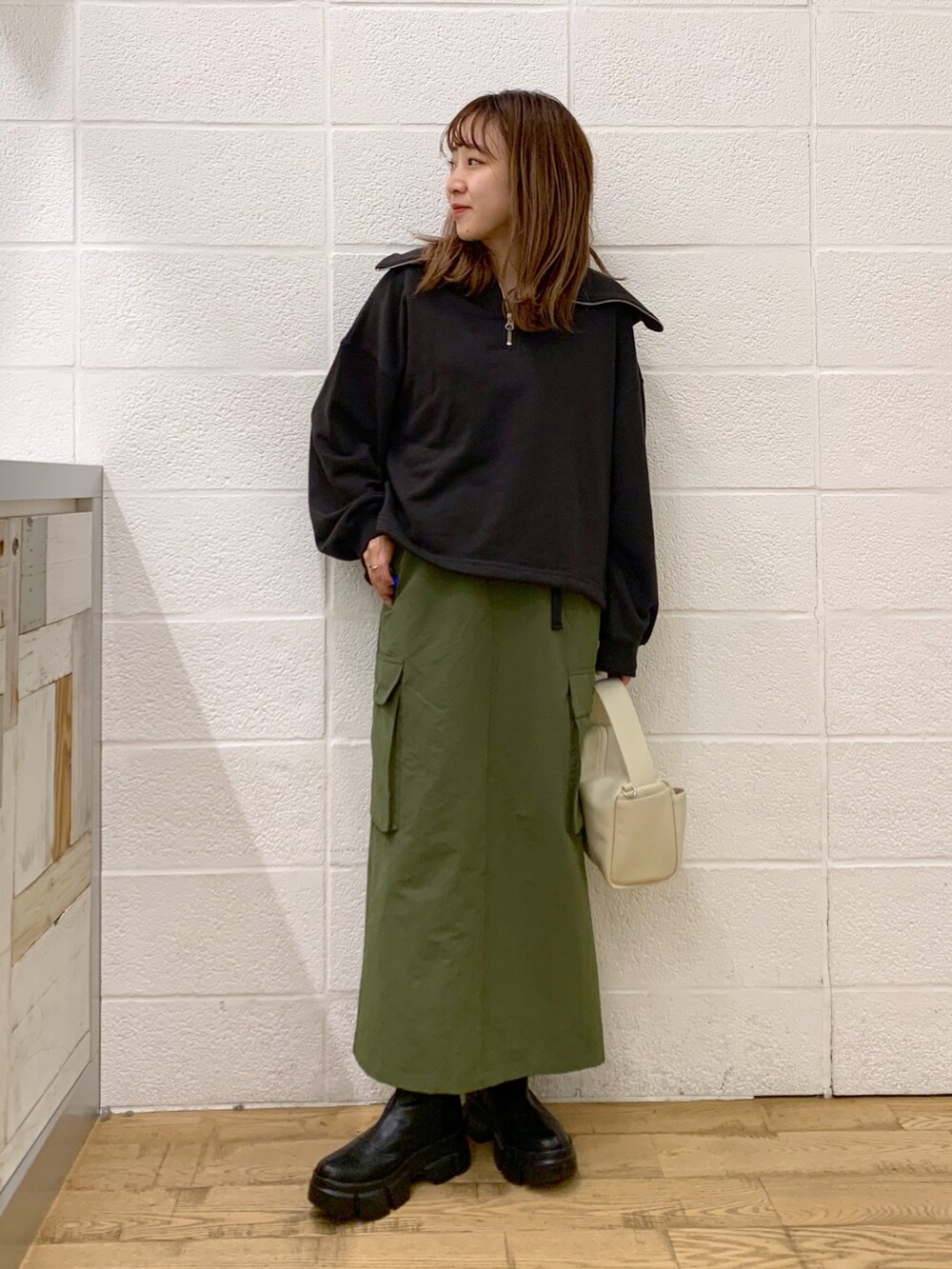 グレー系のトップス、グリーン系のスカート、ホワイト系のバッグを着用したレディースの秋コーディネートの2枚目の写真