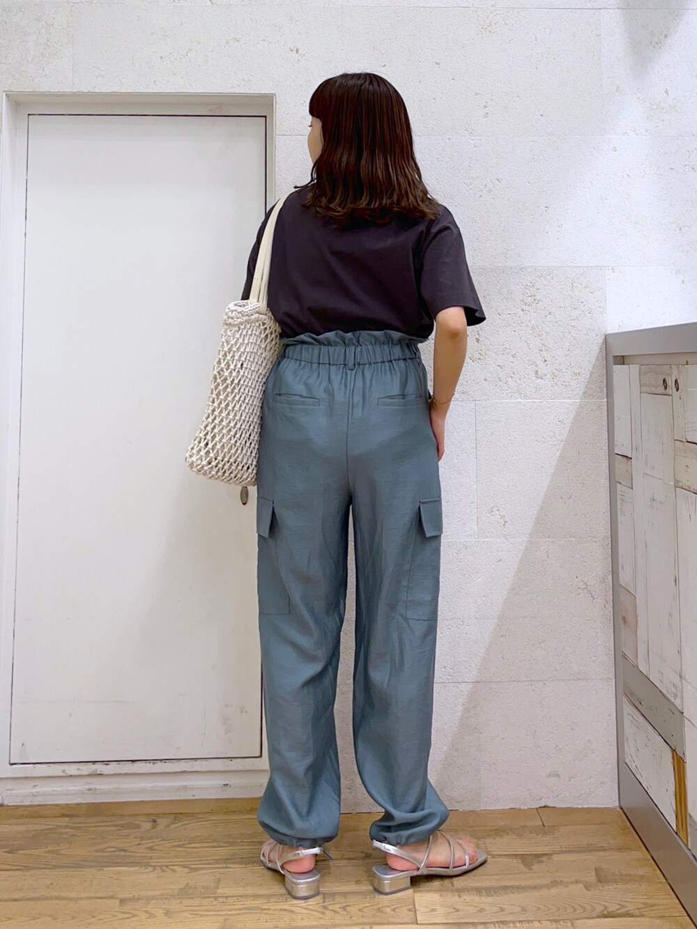 グレー系のトップス、グリーン系のカーゴパンツ、ホワイト系のトートバッグを着用したレディースの春コーディネートの2枚目の写真