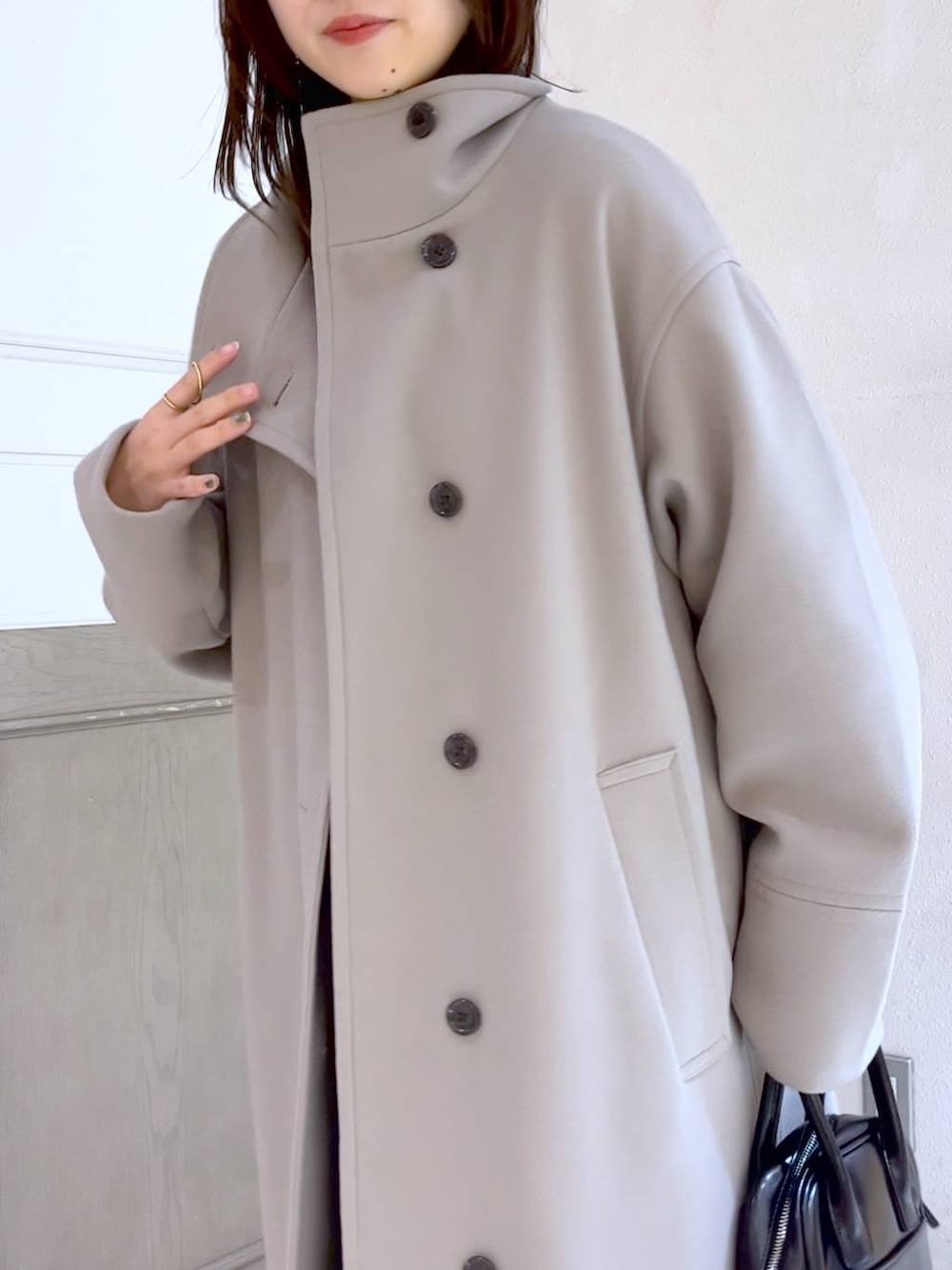 ブラック系のスカート、ホワイト系のチェスターコート、ブラック系のブーツを着用したレディースの冬コーディネートの6枚目の写真