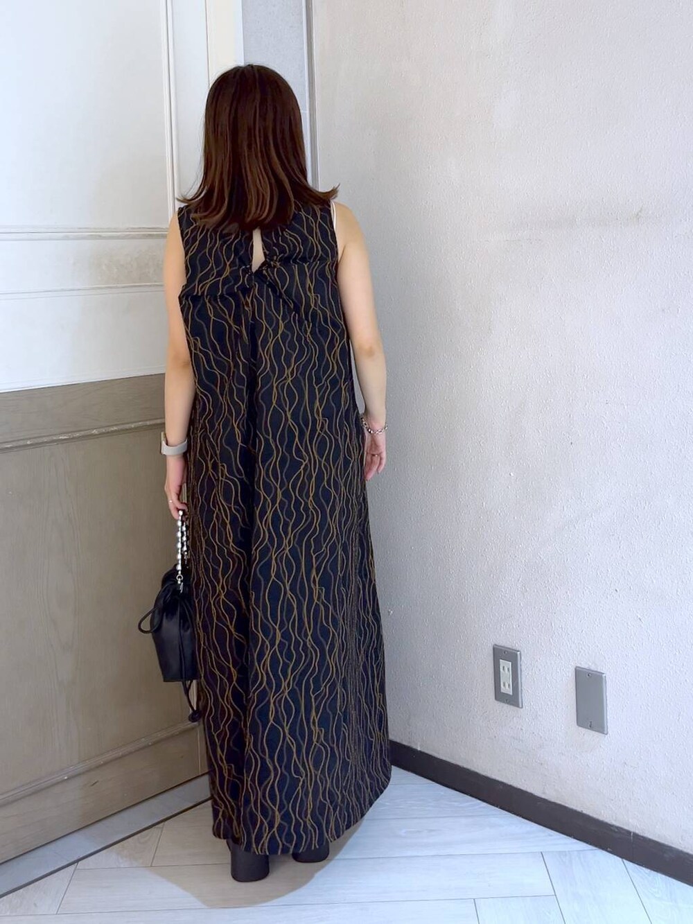 ブラック系のショルダーバッグ、ブラック系のサンダル、ブラック系のワンピースを着用したレディースの夏コーディネートの3枚目の写真