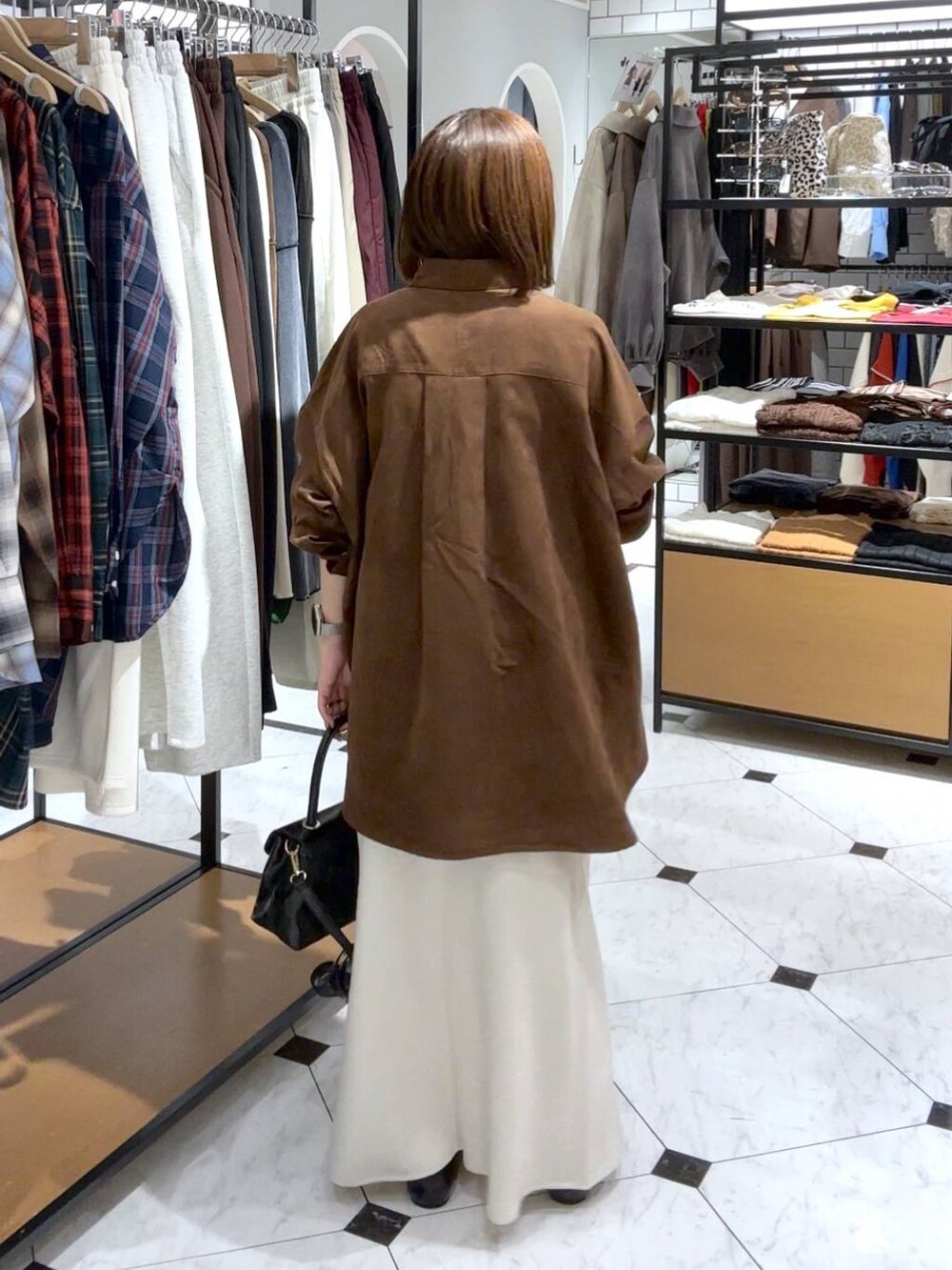 ホワイト系のスカート、ブラック系のボストンバッグ、ブラック系のパンプスを着用したレディースの秋コーディネートの3枚目の写真