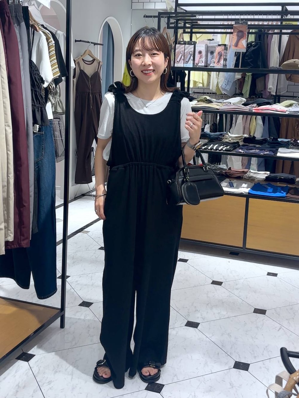 ブラック系のショルダーバッグ、シルバー系のTシャツ/カットソー、ブラック系のサロペット/オーバーオールを着用したレディースの夏コーディネートの3枚目の写真