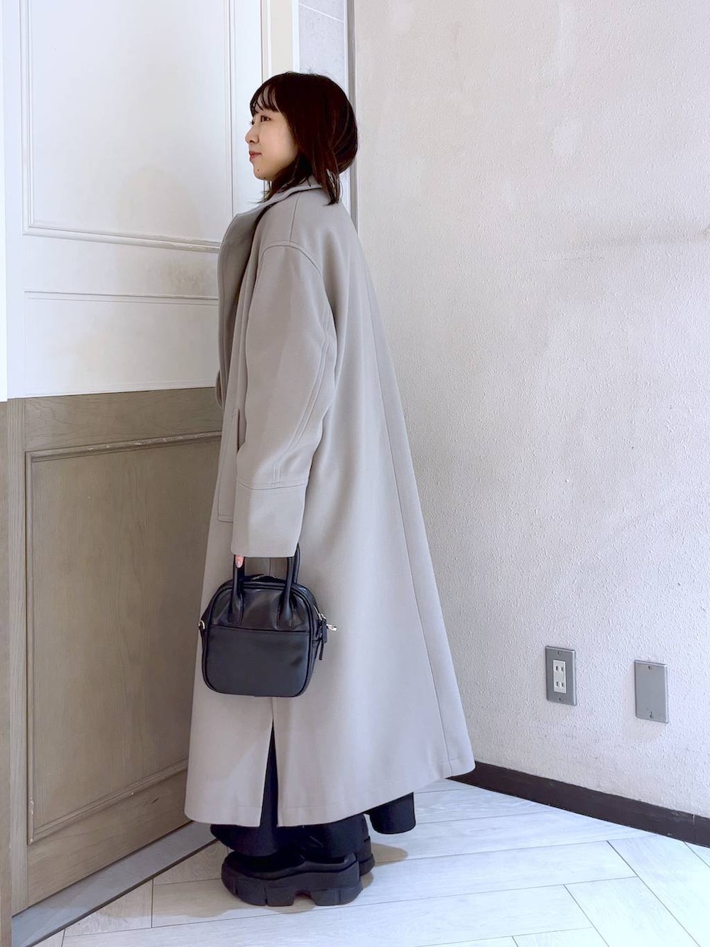 ブラック系のスカート、ホワイト系のチェスターコート、ブラック系のブーツを着用したレディースの冬コーディネートの5枚目の写真