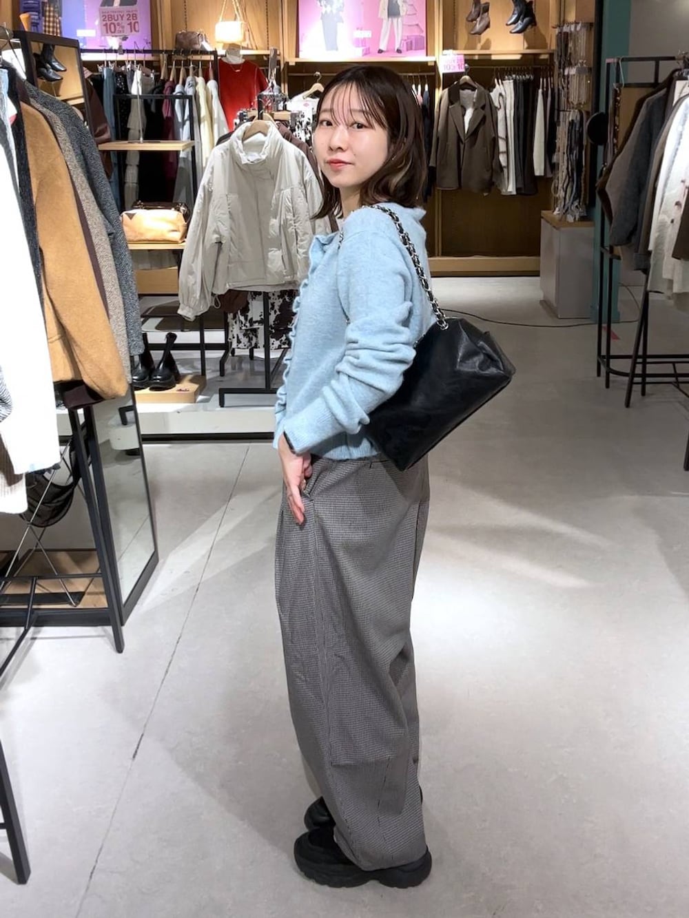 ブルー系のニット/セーター、ブラック系のショルダーバッグを着用したレディースの冬コーディネートの2枚目の写真