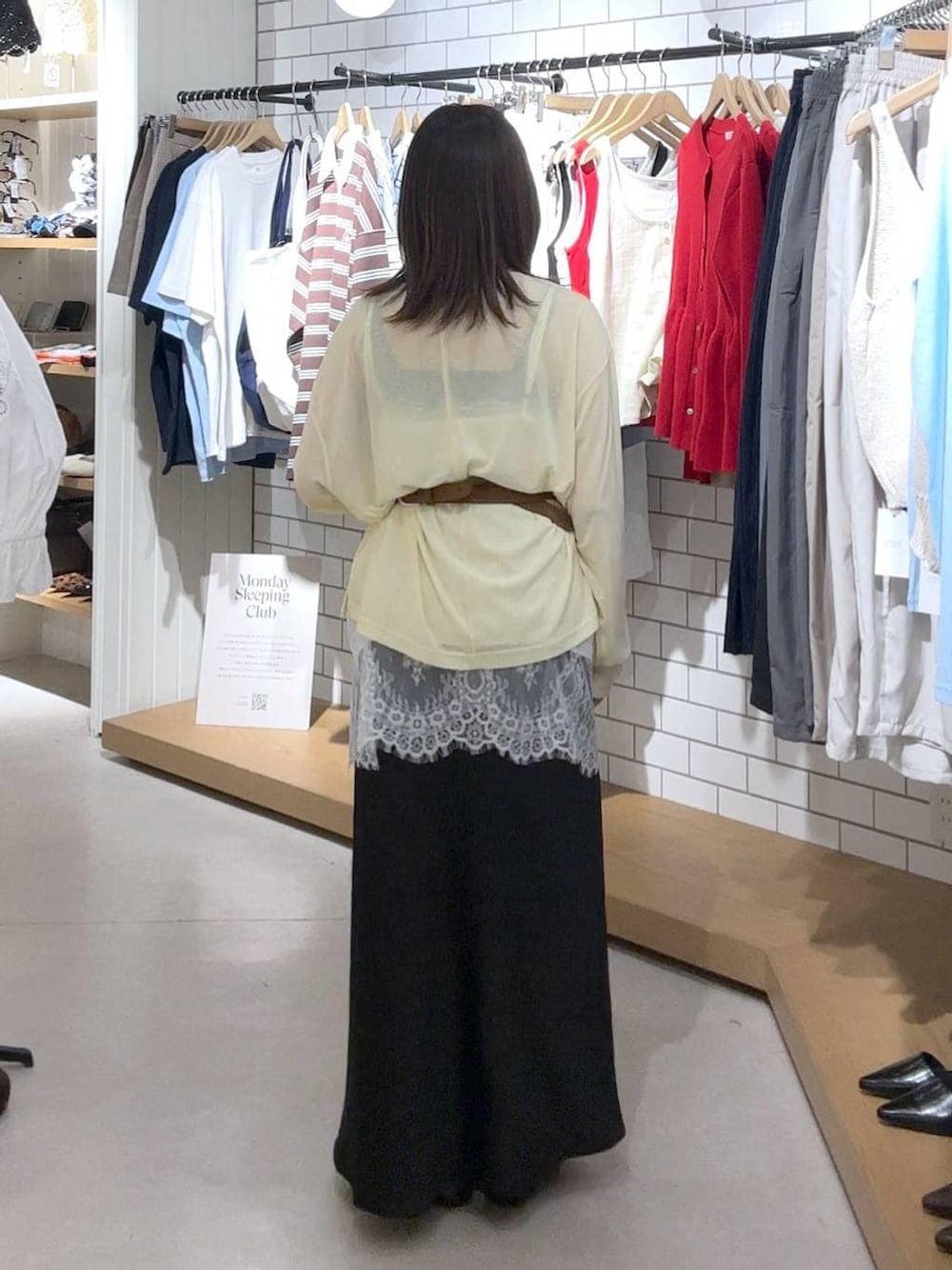 ブラック系のスカート、イエロー系のTシャツ/カットソー、ブラック系のパンプスを着用したレディースの春コーディネートの3枚目の写真