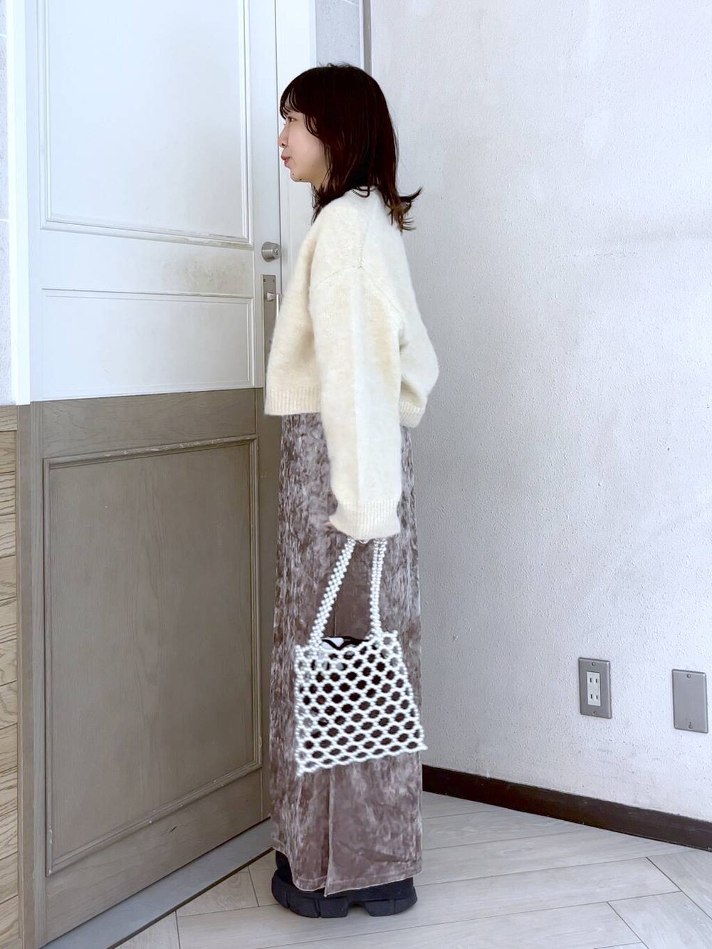 ブラック系のブーツ、ピンク系のスカート、ホワイト系のショルダーバッグを着用したレディースの冬コーディネートの3枚目の写真