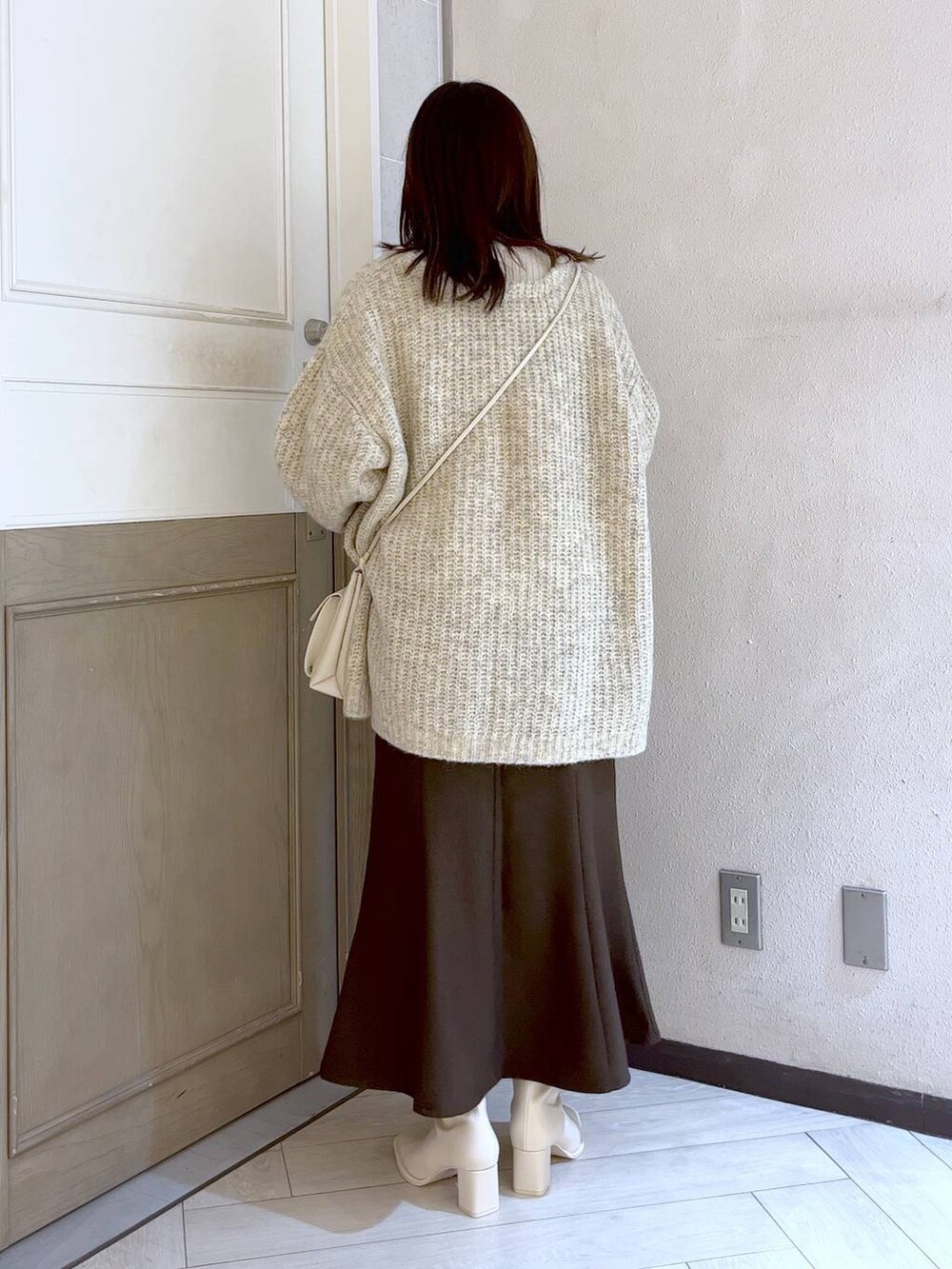 ホワイト系のショルダーバッグ、ブラウン系のスカート、ホワイト系のパンプスを着用したレディースの冬コーディネートの4枚目の写真