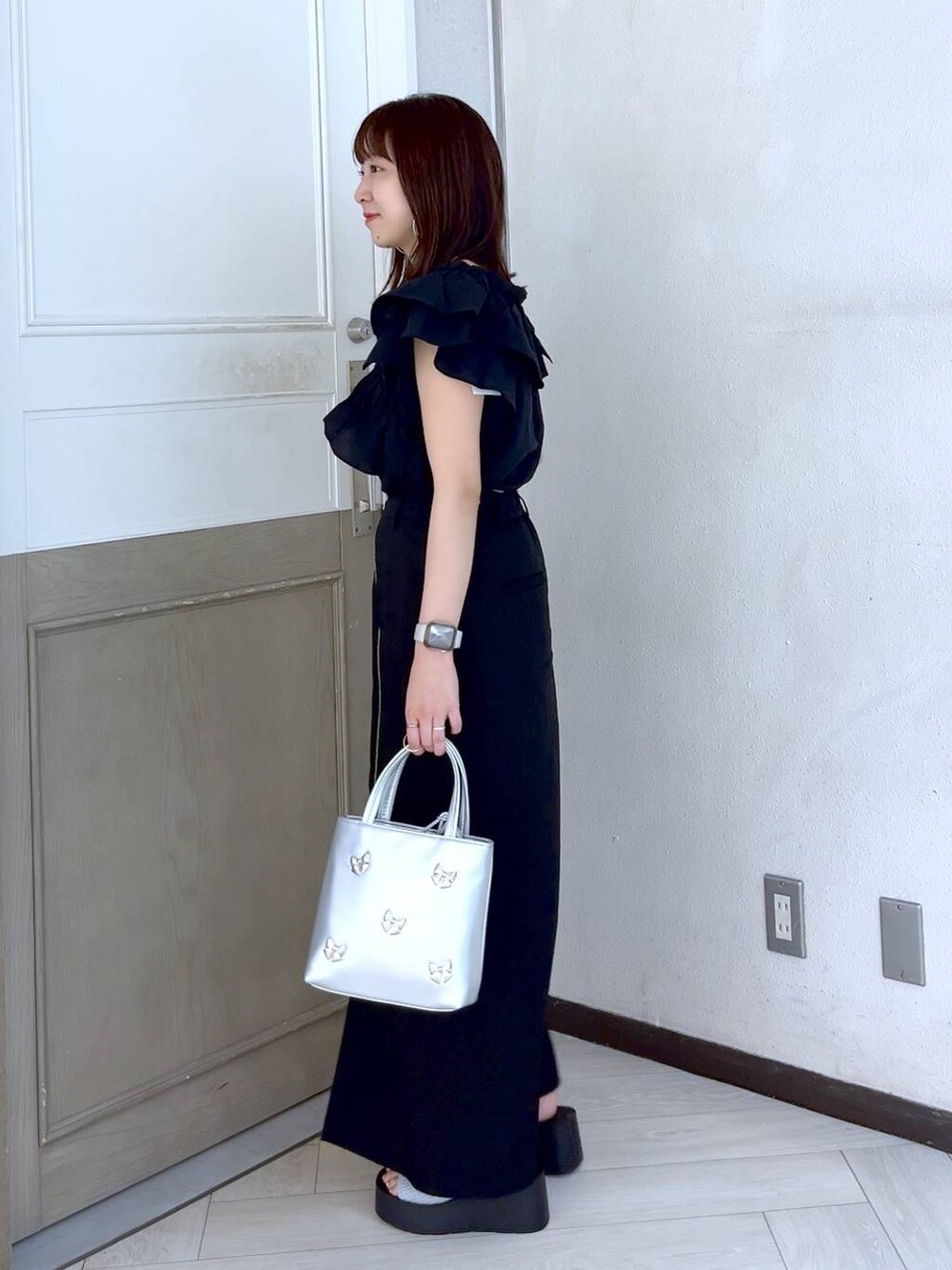 シルバー系のサンダル、シルバー系のショルダーバッグ、ブラック系のスカートを着用したレディースの夏コーディネートの2枚目の写真