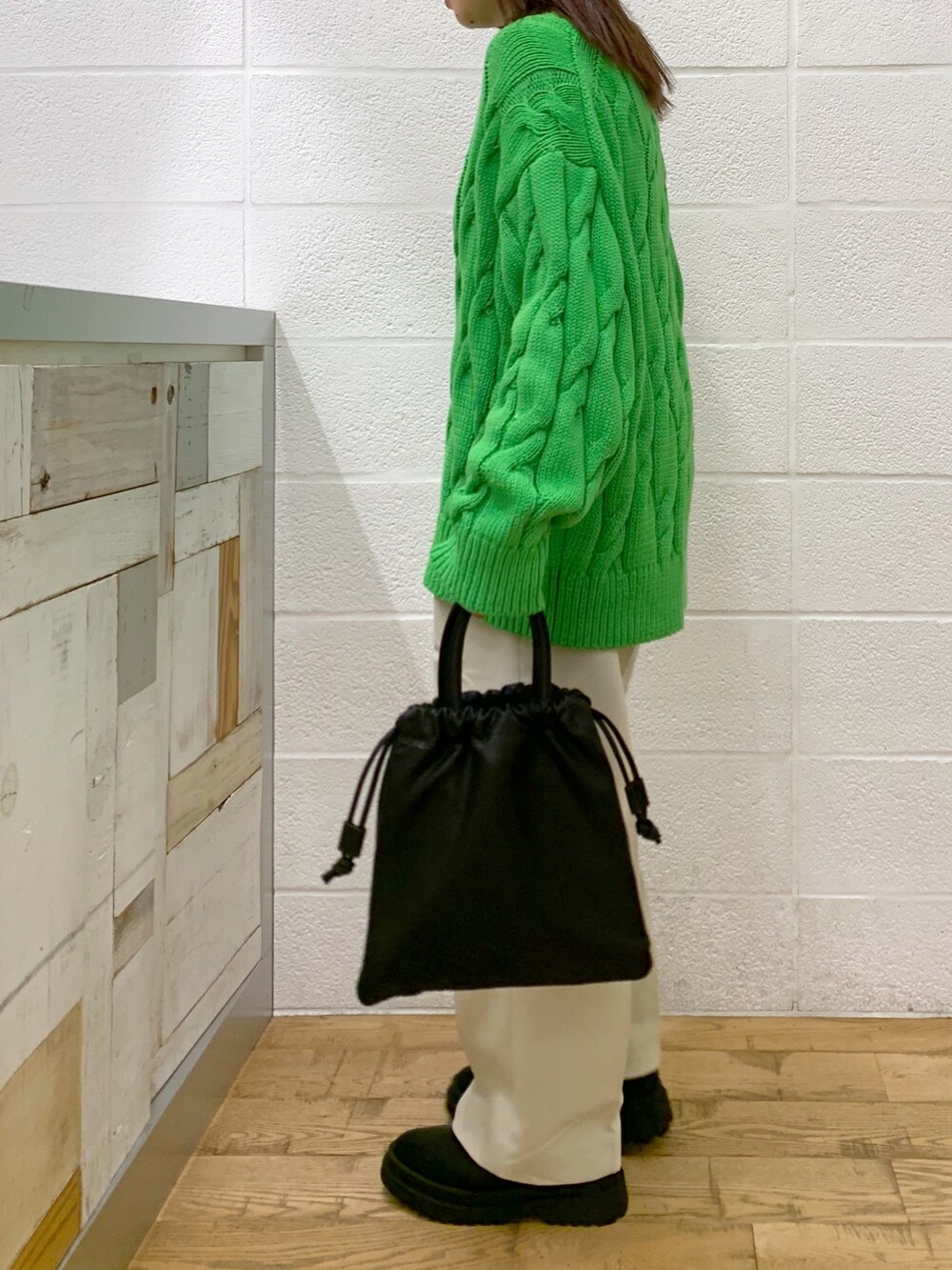 グリーン系のトップス、ブラック系のショルダーバッグ、ブルー系のパンツを着用したレディースの秋コーディネートの2枚目の写真