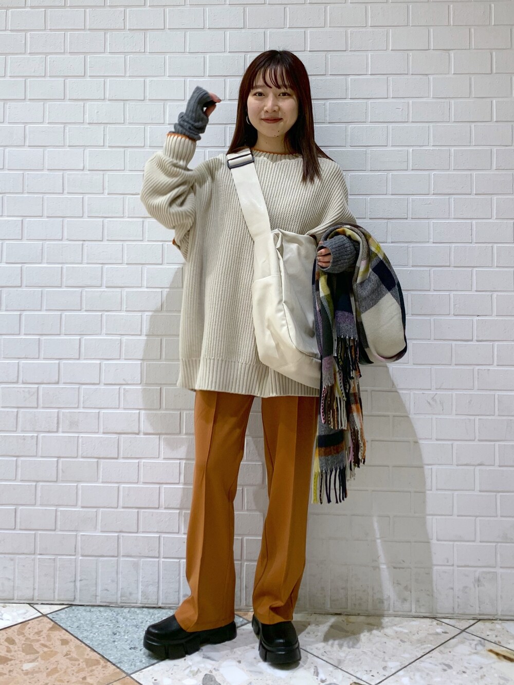 ブラウン系のニット/セーター、オレンジ系のパンツ、ホワイト系のバッグを着用したレディースの冬コーディネートの3枚目の写真
