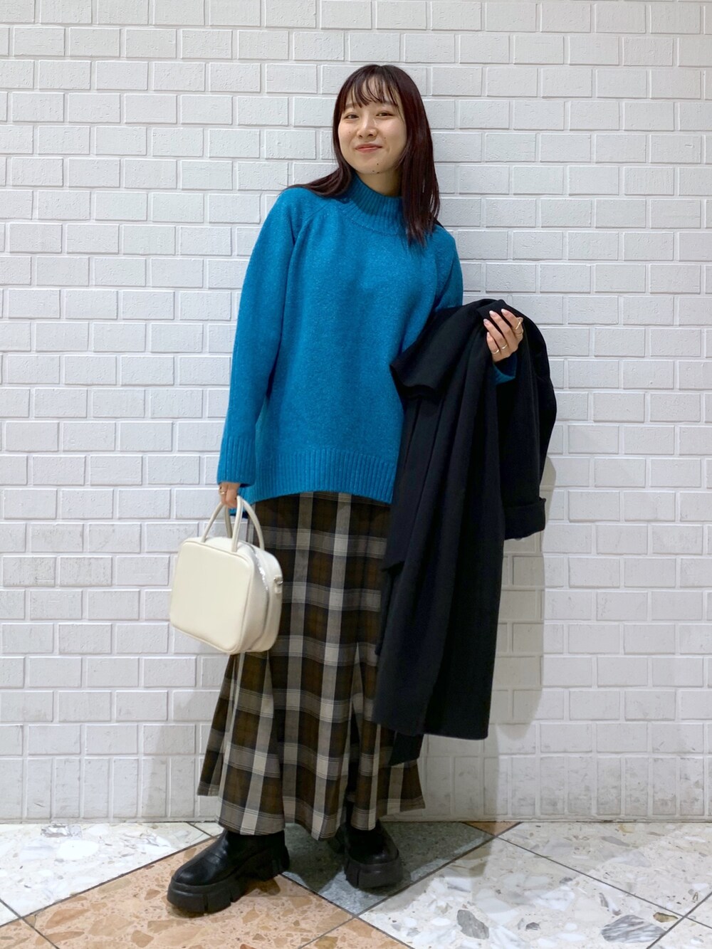 ブラック系のジャケット/アウター、ブルー系のトップス、ブラウン系のスカートを着用したレディースの冬コーディネートの5枚目の写真
