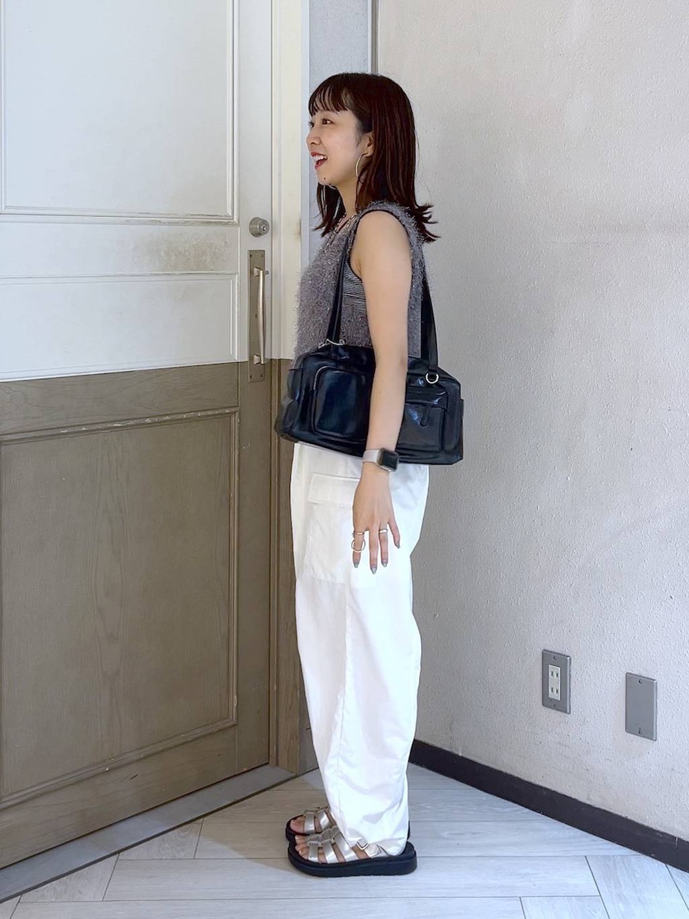 ホワイト系のカーゴパンツ、ブラック系のボストンバッグ、シルバー系のスニーカーを着用したレディースの夏コーディネートの3枚目の写真