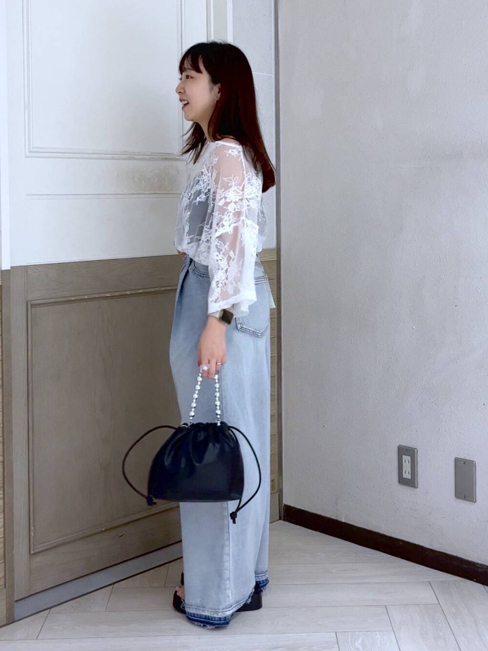 ブルー系のデニムパンツ、シルバー系のサンダル、ブラック系のショルダーバッグを着用したレディースの夏コーディネートの3枚目の写真