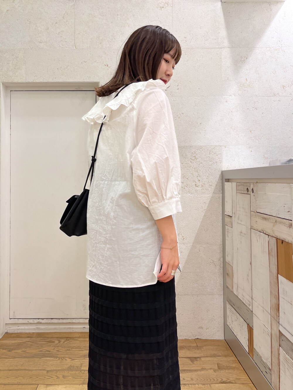ホワイト系のトップス、ブラック系のスカート、ブラック系のバッグを着用したレディースの春コーディネートの4枚目の写真