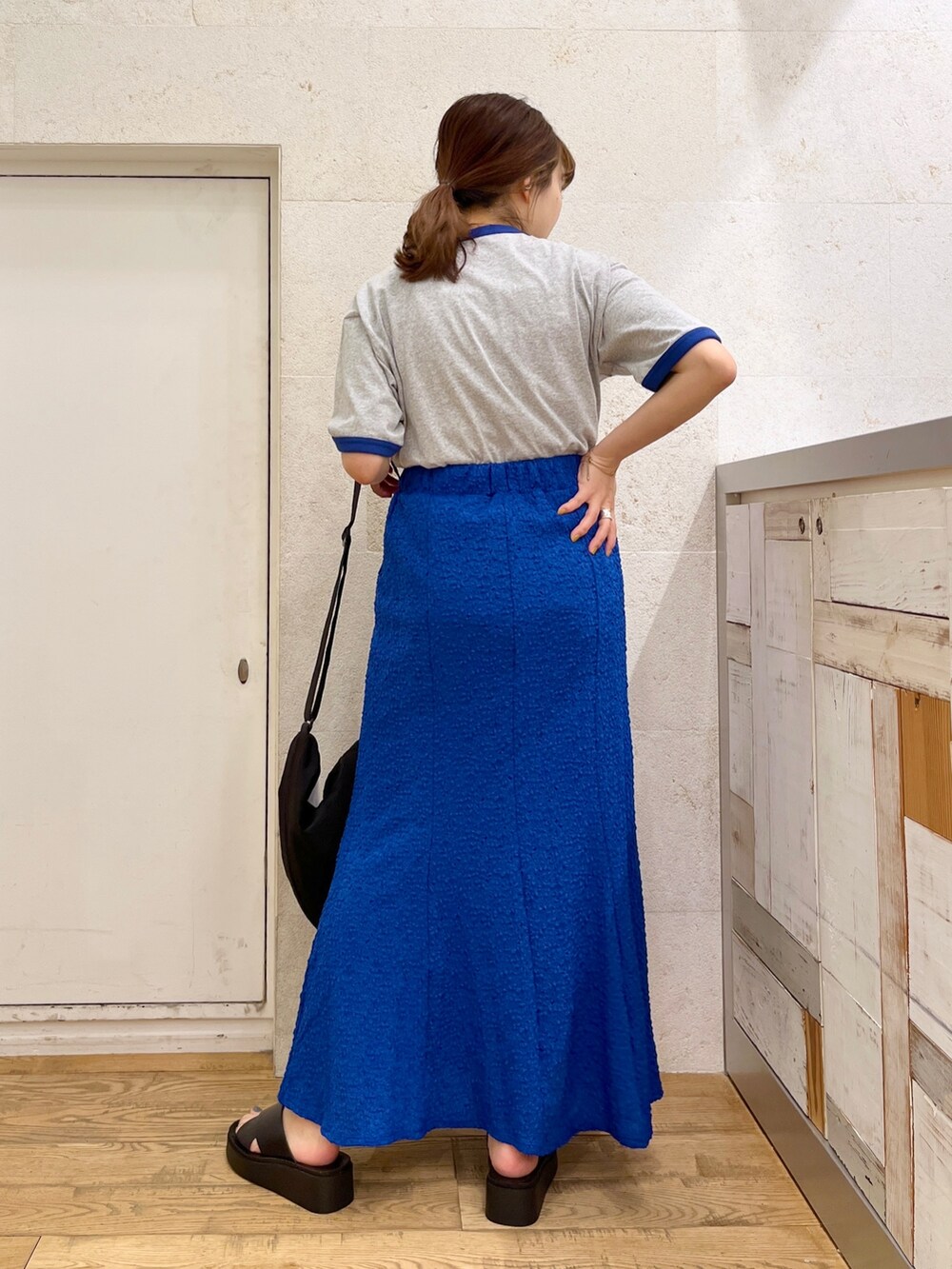 グレー系のTシャツ/カットソー、ブルー系のスカート、ブラック系のシューズを着用したレディースの春コーディネートの4枚目の写真