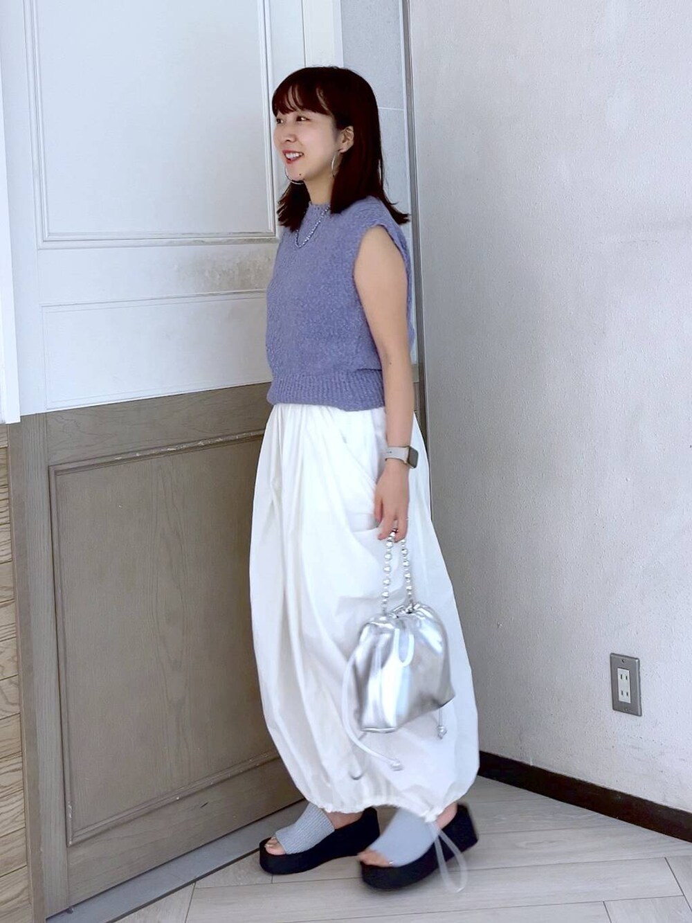 シルバー系のサンダル、ホワイト系のスカート、シルバー系のショルダーバッグを着用したレディースの夏コーディネートの3枚目の写真