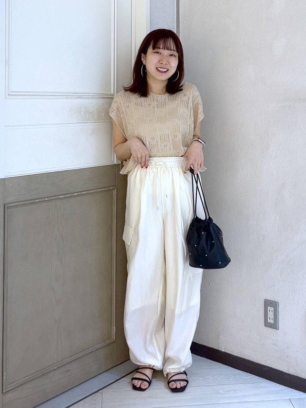 ホワイト系のカーゴパンツ、ブラック系のショルダーバッグ、ブラック系のサンダルを着用したレディースの夏コーディネートの3枚目の写真