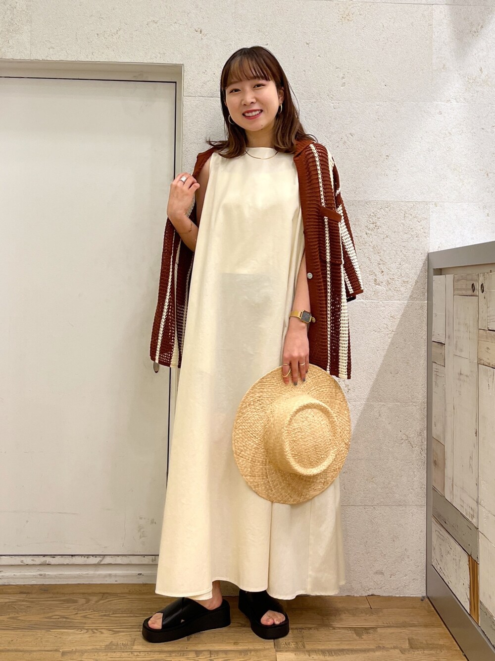 ホワイト系のワンピース、ブラウン系のトップス、ブラック系のシューズを着用したレディースの春コーディネートの3枚目の写真